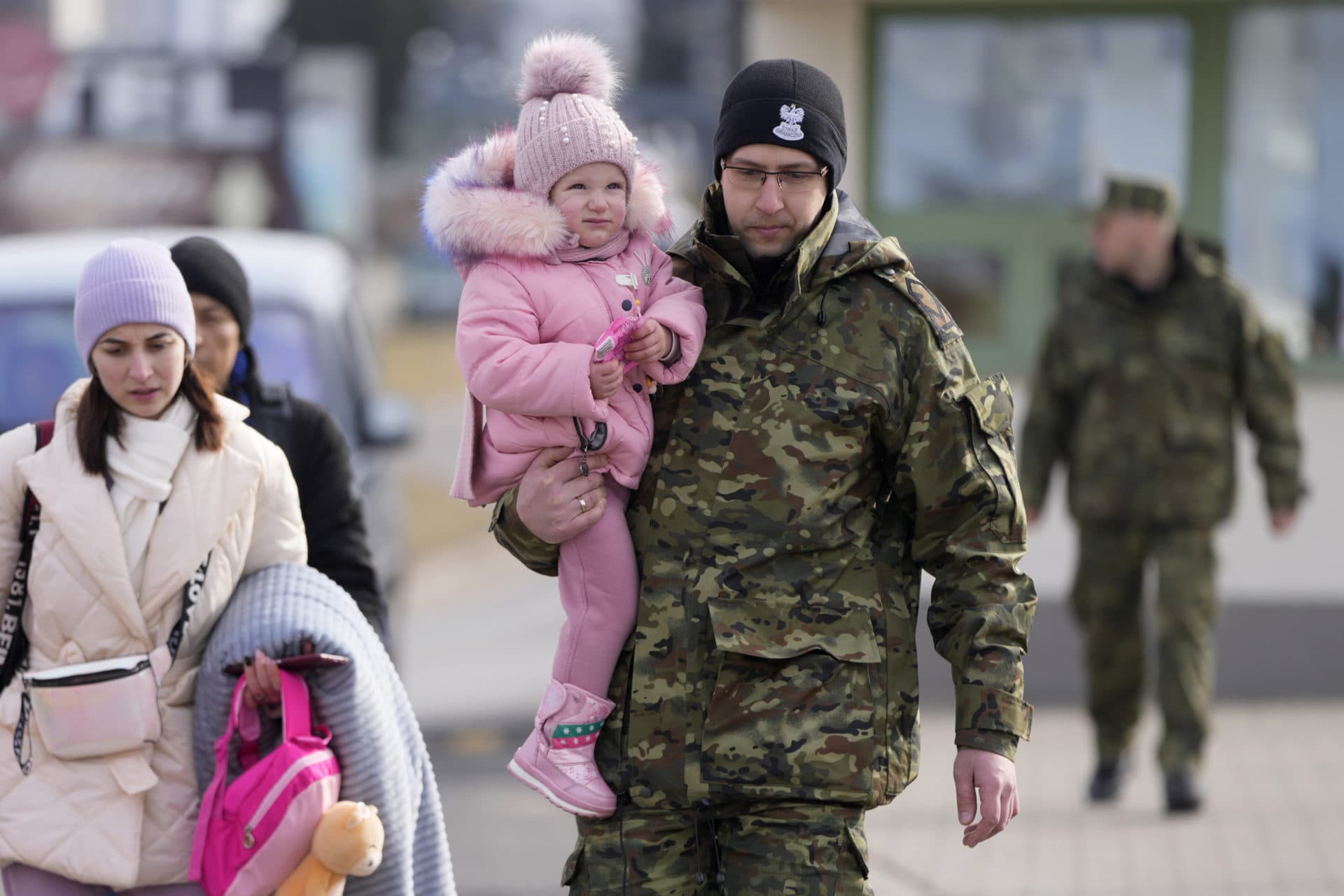 A Polish border guard carries a child as refugees from Ukraine cross into Poland at the Medyka crossing on March 1. (Markus Schreiber/AP)