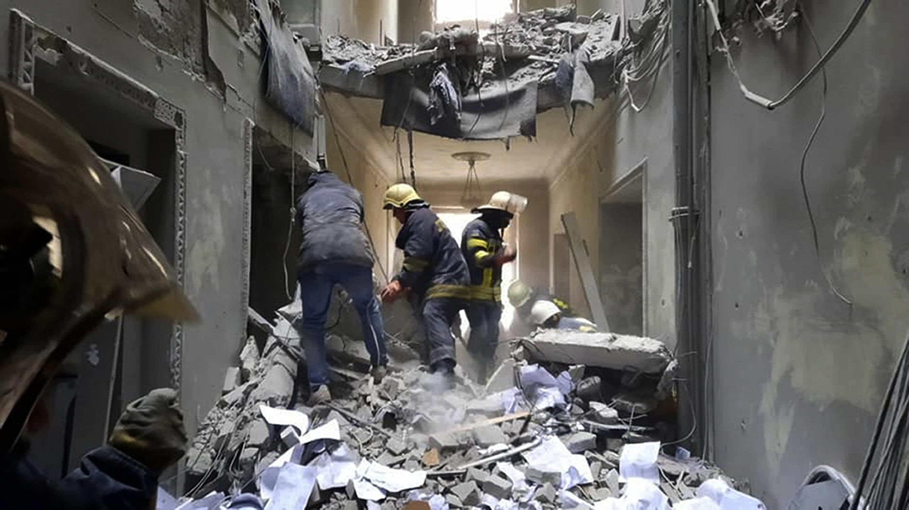 This handout photo released by Ukrainian Emergency Service shows emergency service personnel inspecting the damage inside the City Hall building in Kharkiv, Ukraine on March 1. (Ukrainian Emergency Service via AP)