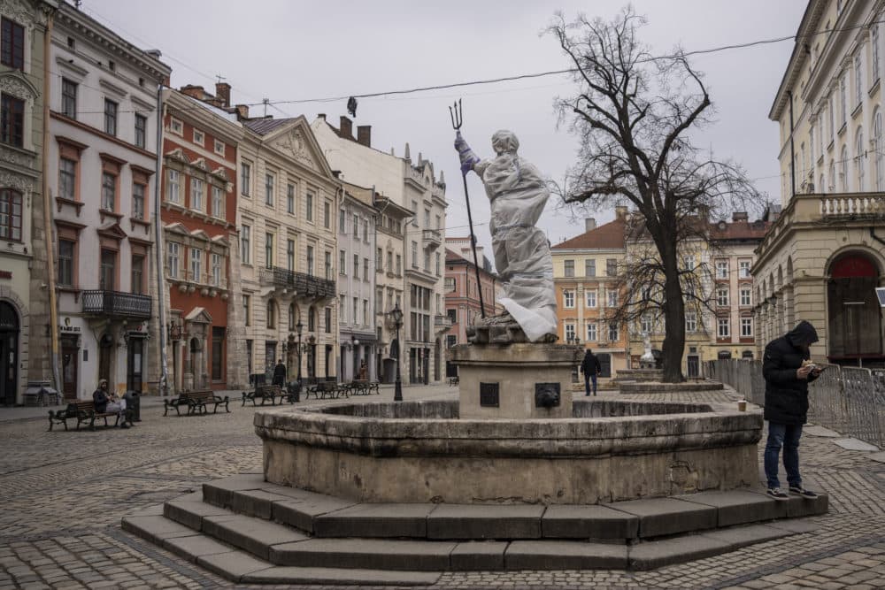 A man stands next to a wrapped sculpture in Lviv's downtown, western Ukraine, on March 4. Some of the monuments in Lviv are partially covered to lower the risk of damage in case of attacks in the city. (AP Photo/Bernat Armangue)