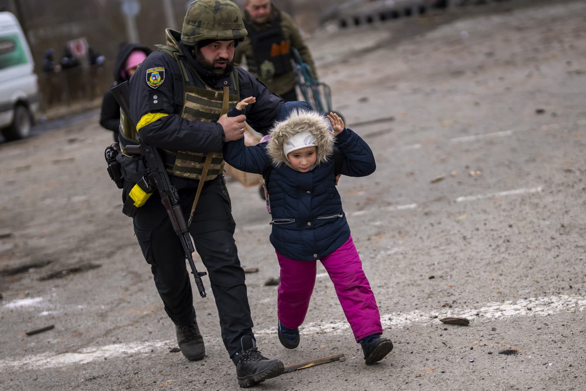 A Ukrainian police officer runs while holding a child as the artillery echoes nearby, while fleeing Irpin on the outskirts of Kyiv, Ukraine, Monday, March 7, 2022. (Emilio Morenatti/AP)