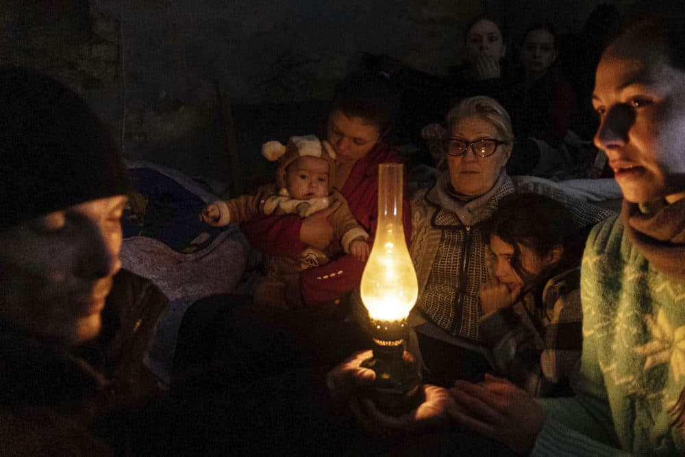 People sit around a lamp in a bomb shelter in Mariupol, Ukraine, Sunday, March 6, 2022. (Evgeniy Maloletka/AP)