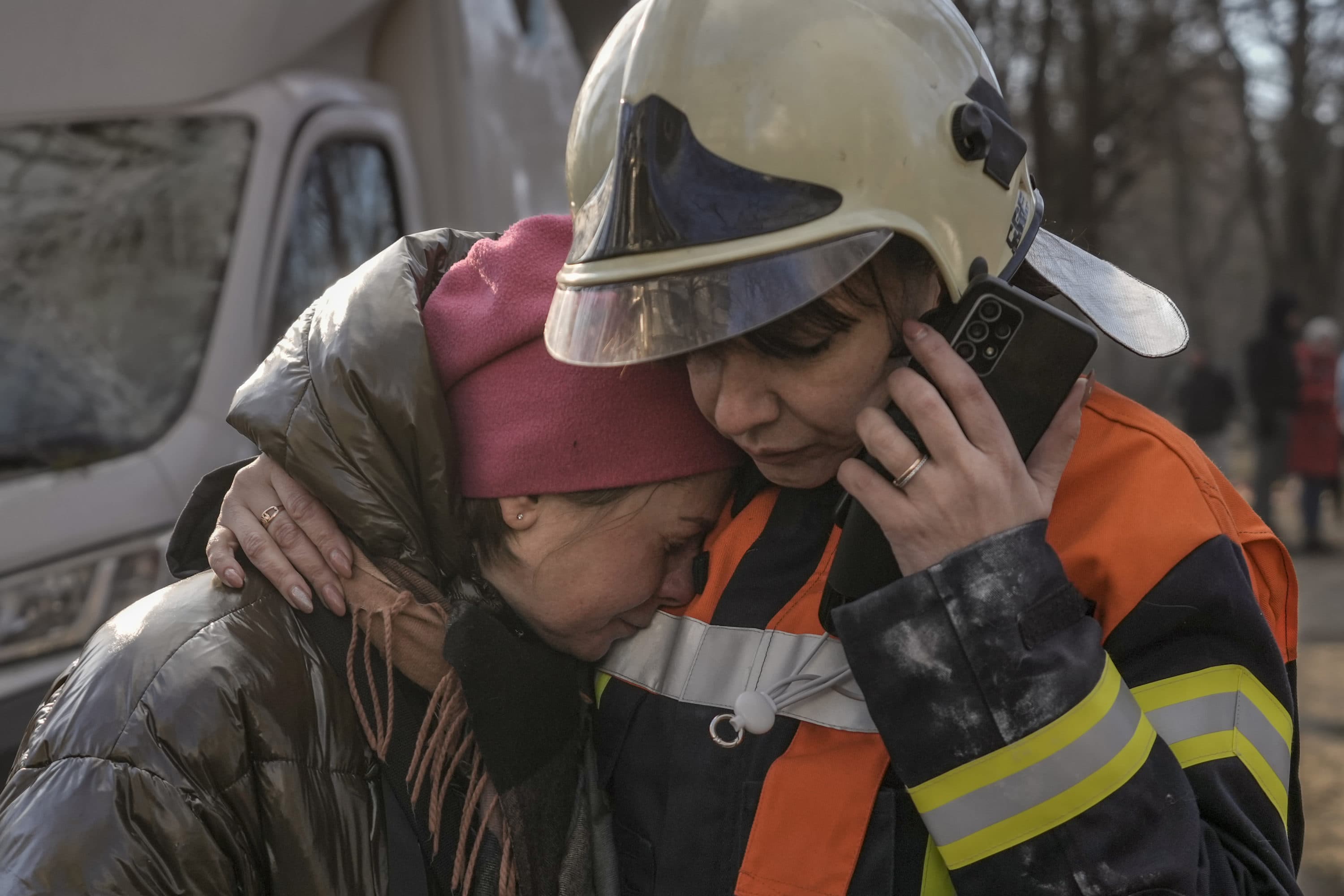 A firefighter comforts a woman outside a destroyed apartment building after a bombing in a residential area in Kyiv, Ukraine, Tuesday, March 15, 2022. (Vadim Ghirda/AP)