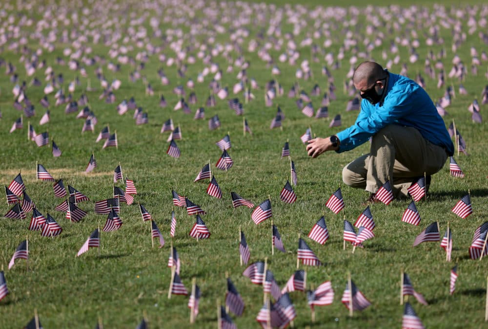 A man whose mother died from COVID photographs a COVID Memorial Project installation of 20,000 American flags on the National Mall when the U.S. marked 200,000 lives lost in the COVID-19 pandemic in September of 2020. (Win McNamee/Getty Images)