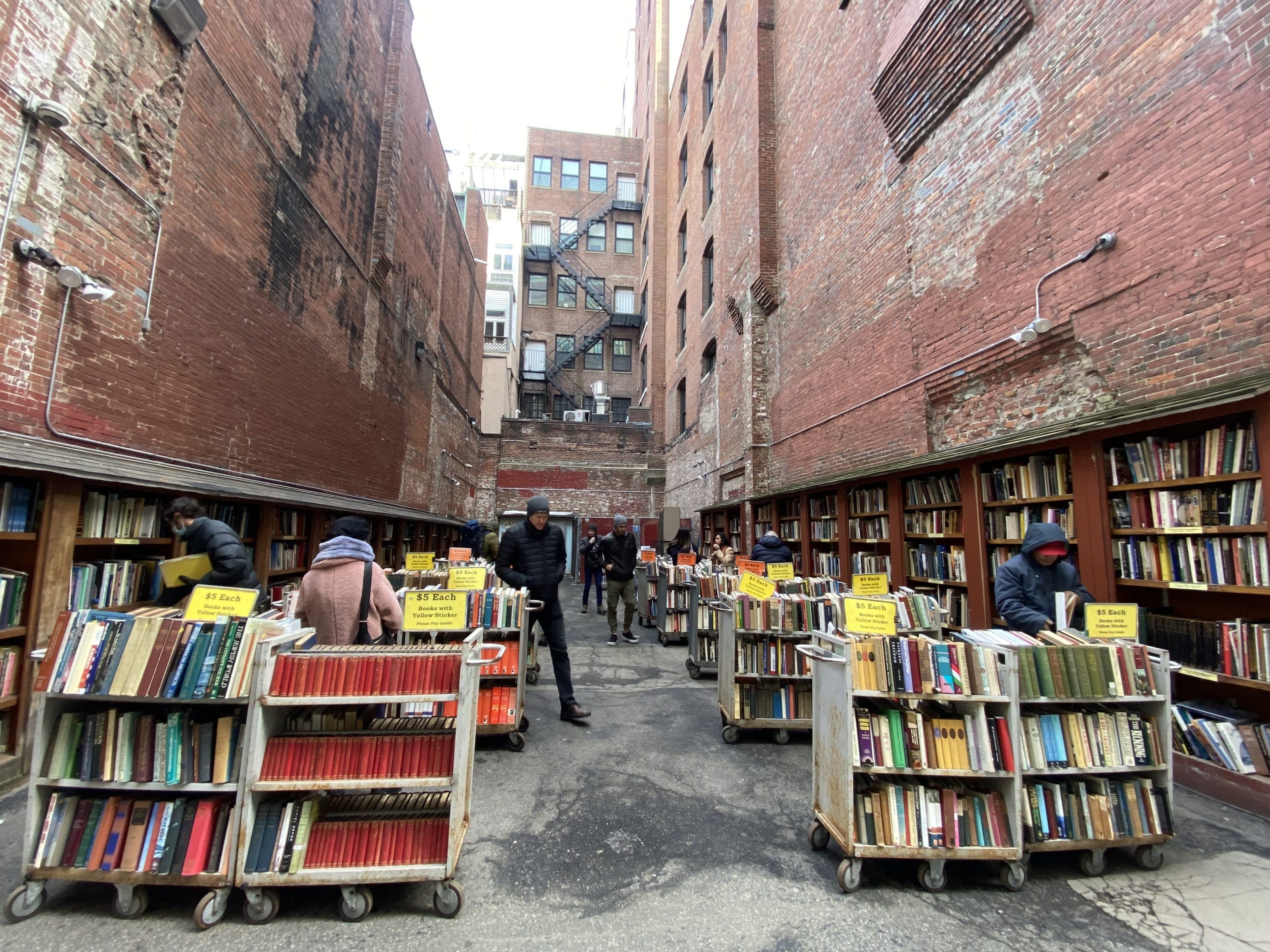 Customers peruse book while at the outside portion of the Brattle Book Shop on March 5 — the day that Boston lifted its mask mandate for businesses and restaurants. (Amanda Beland/WBUR)