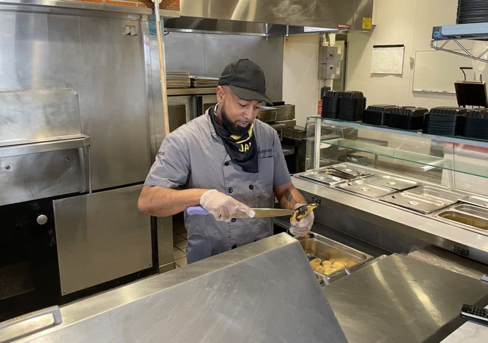 Executive chef of Jamaica Mi Hungry Jason Gentles cuts up plantains at the restaurant's Allston location. (Darryl C. Murphy/WBUR)