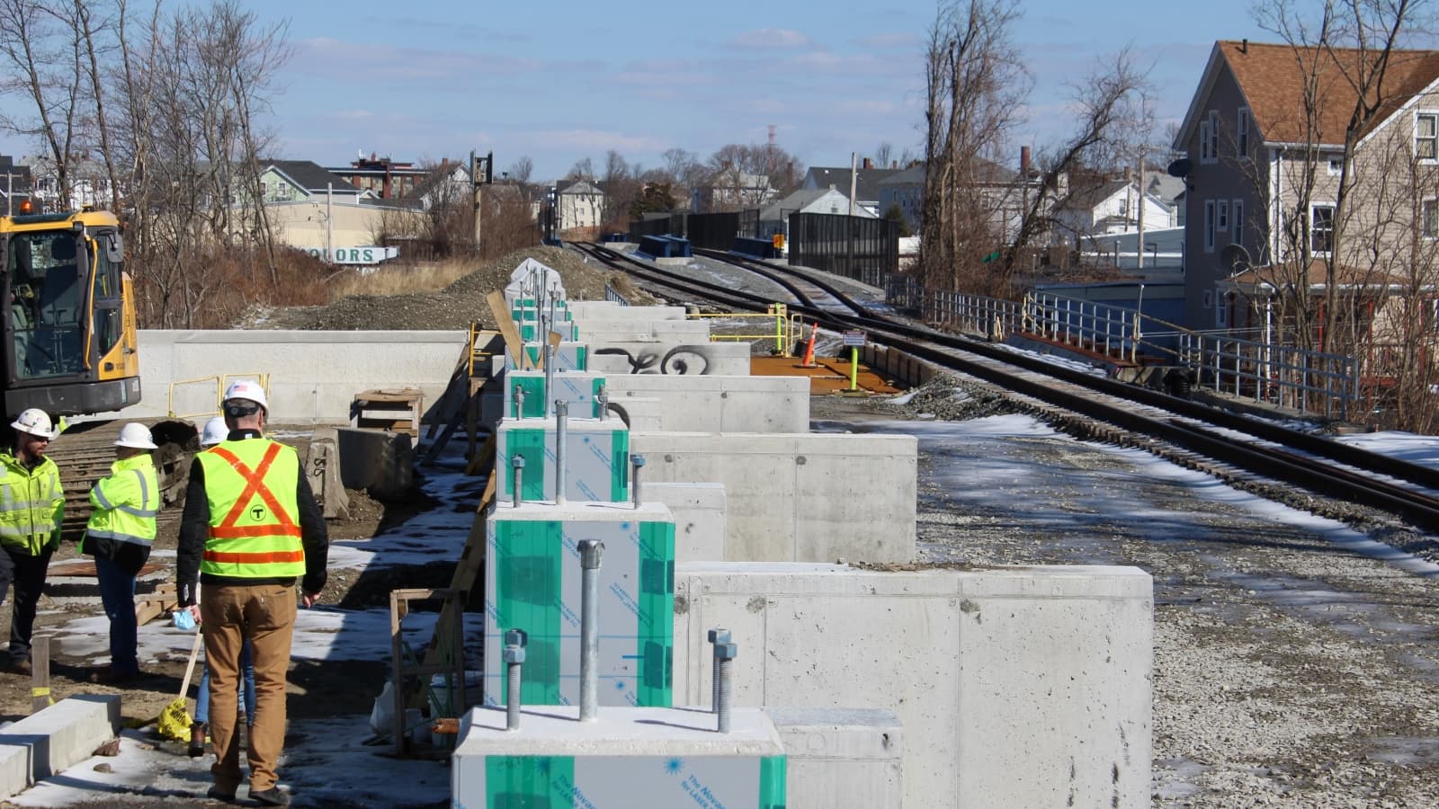 This photo is of an MBTA construction site on the South Coast, with three people in green vests next to stood-up concrete slabs. It was taken by Ben Berke for The Public's Radio.