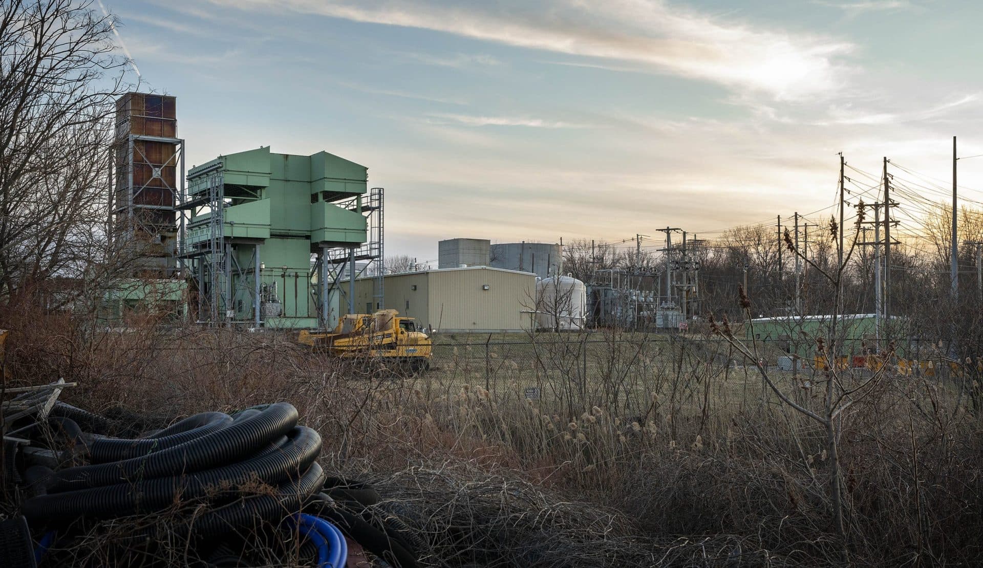 The Peabody Municipal Light Plant’s Waters River substation on Pulaski Street currently has two gas peaker power plants. The Massachusetts Municipal Wholesale Electric Company has approval to build a third plant in the flat grassy area where the two yellow trucks are parked. (Robin Lubbock/WBUR)