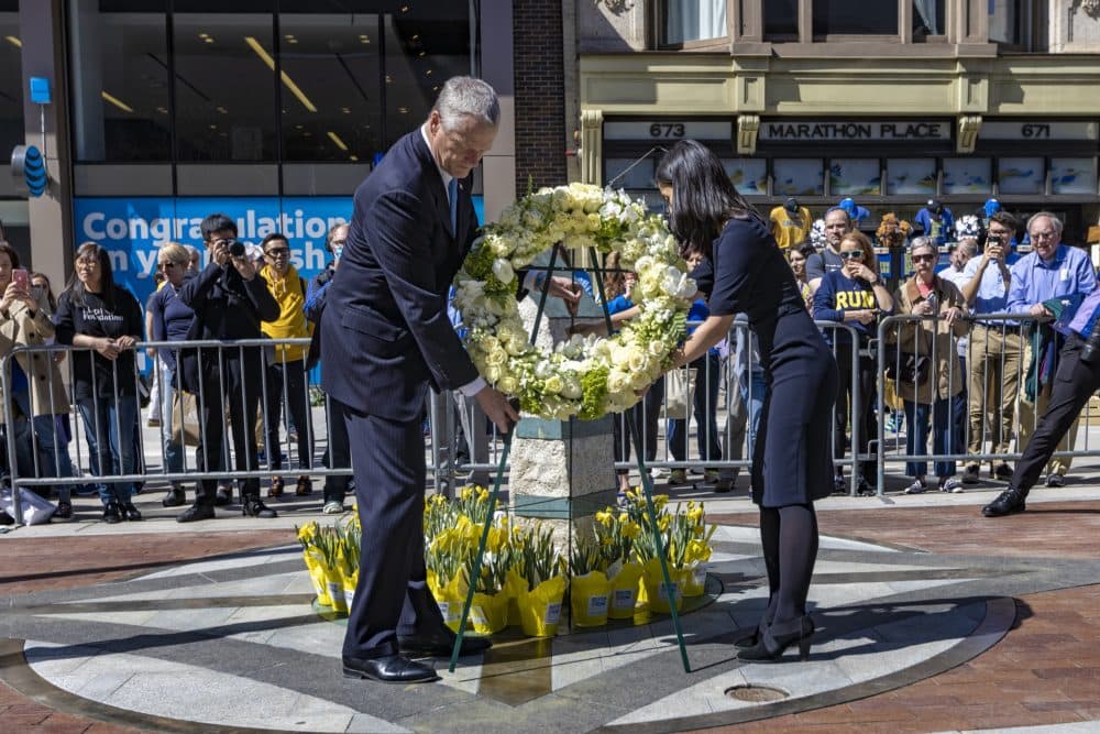 Gov. Charlie Baker and Mayor Michelle Wu place a wreath of flowers at the Marathon Bombing Memorial at 671 Boylston St., the site of the first bomb explosion. (Jesse Costa/WBUR)