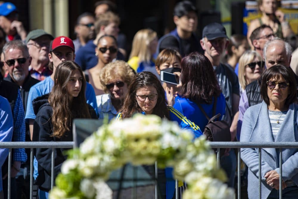People gathered at the Marathon Bombing Memorial at 671 Boylston St. during the moment of silence as the bells toll from Old South Church. (Jesse Costa/WBUR)