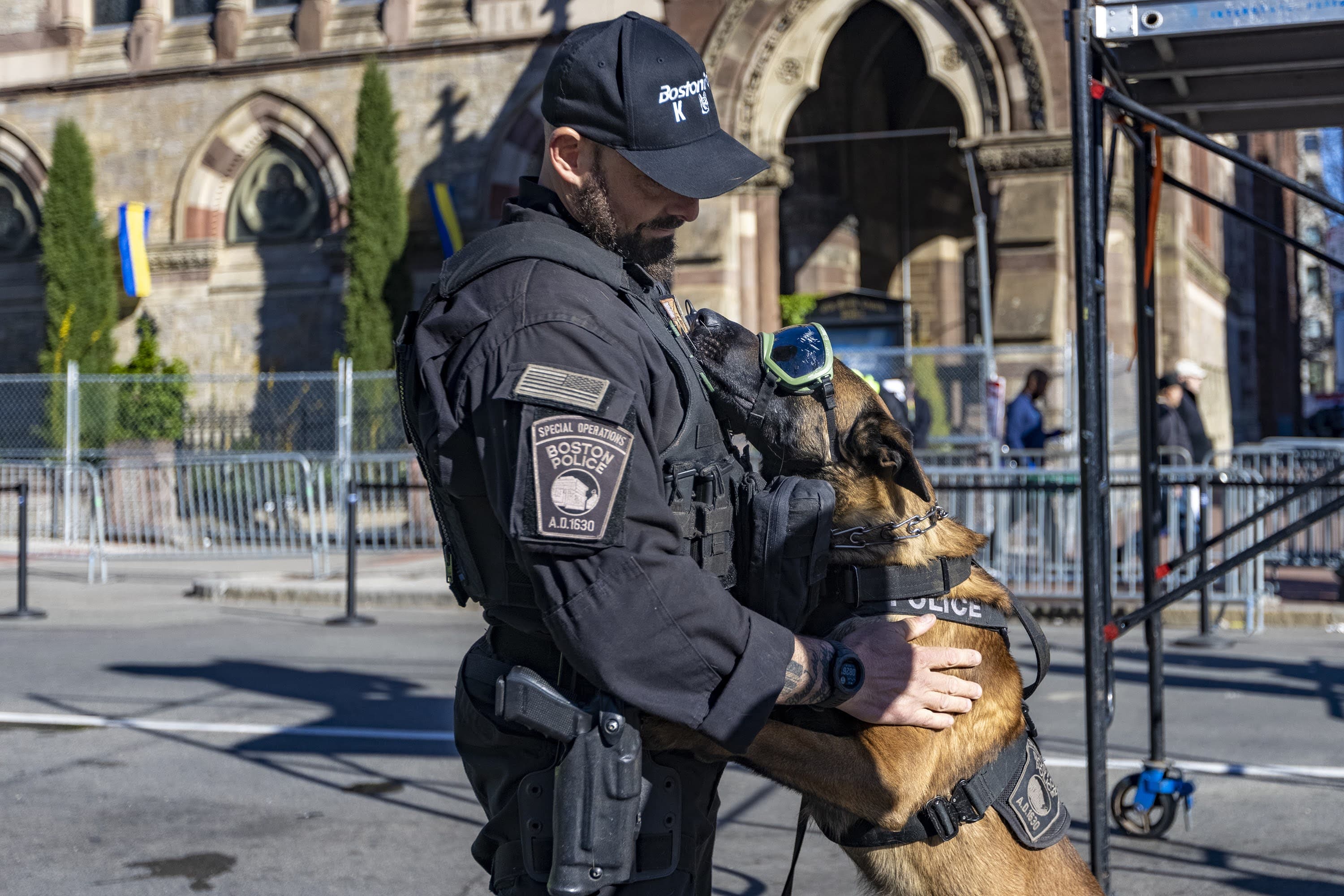 Boston K-9 police officer Gregg Bowdoin and Mr. Wick have a playful moment at the finish line on Boylston Street as crews prepare for the race. (Jesse Costa/WBUR)