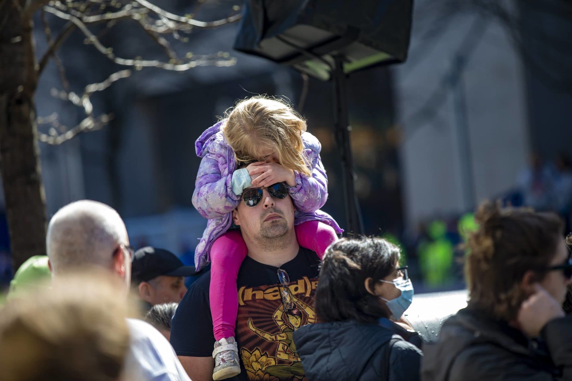 Five-year-old Jane Dawson waits for the wheelchair racers to finish on the shoulders of her stepfather Jordan Duguay by the finish line on Boylston Street. (Jesse Costa/WBUR)