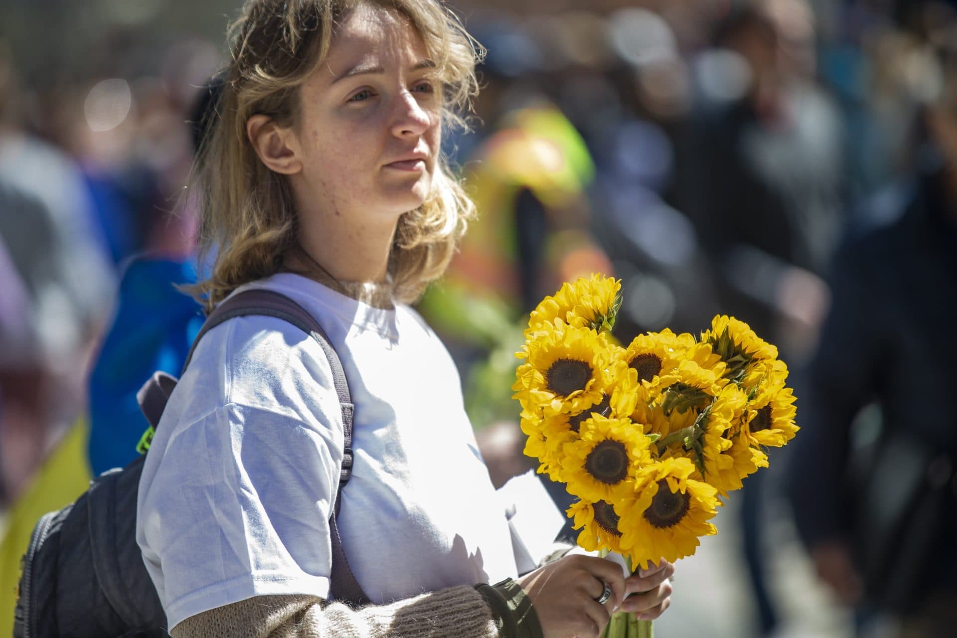 Yulia Kosheleva holds a bunch of flowers she is handing out to raise donations for the people of Ukraine. (Jesse Costa/WBUR)