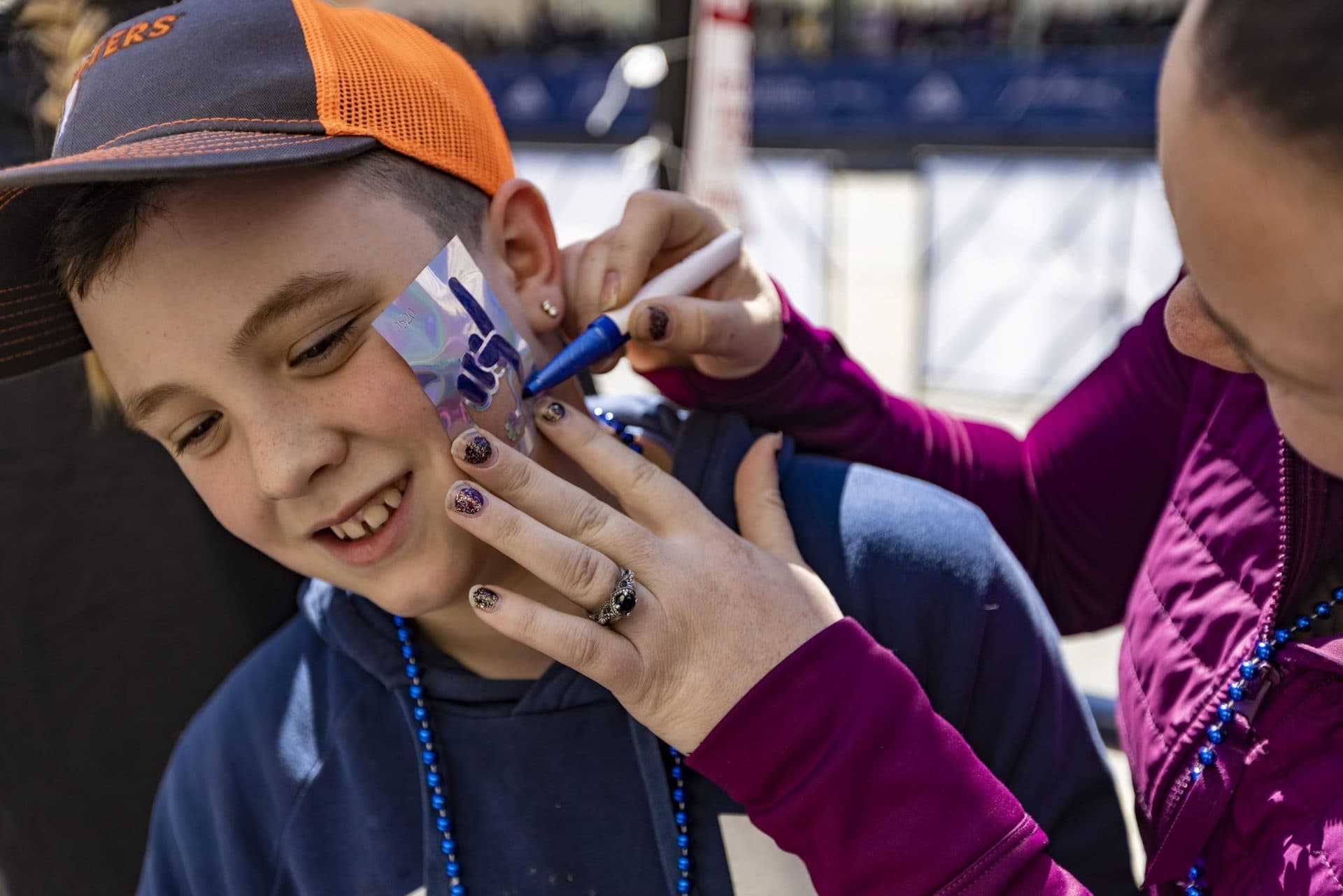 Ayden Porter gets a “Number 1 finger” face tattoo from his mother Jackie on Boylston Street. (Jesse Costa/WBUR)