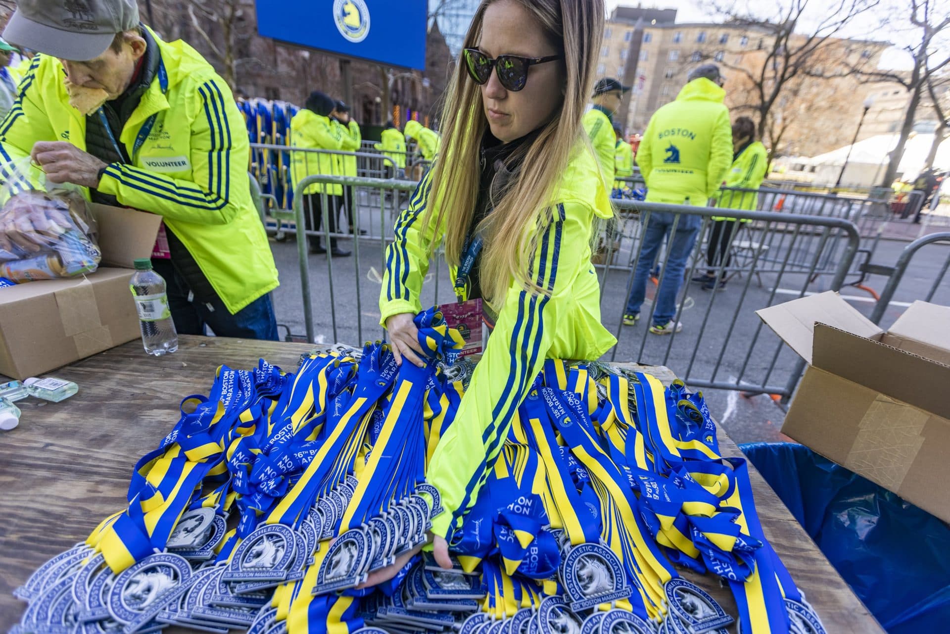 Kayla Biagioni unpacks medals onto a table on Boylston Street. (Jesse Costa/WBUR)
