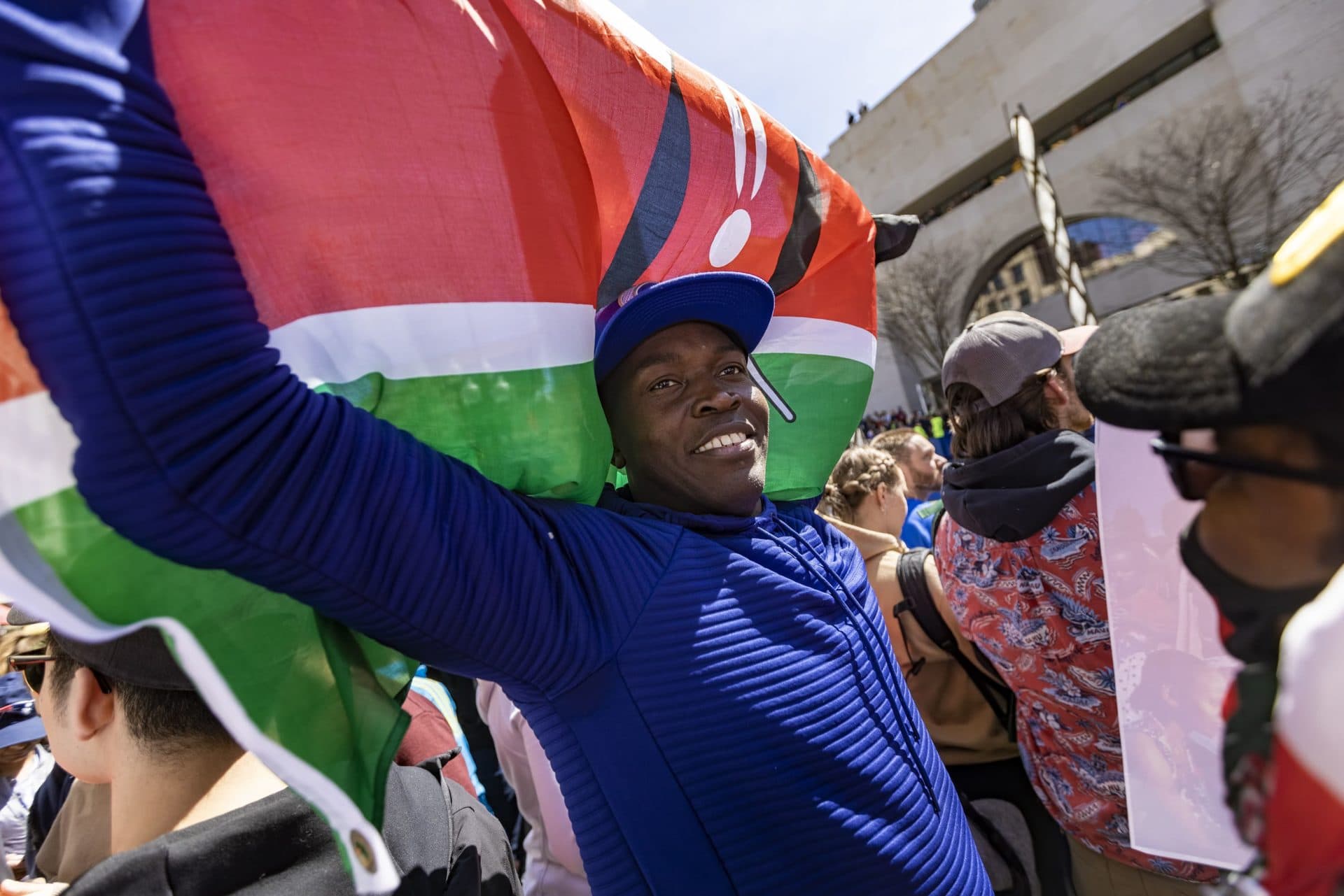Dan Akeyo waves a Kenyan Flag at the Boston Marathon finish line. (Jesse Costa/WBUR)