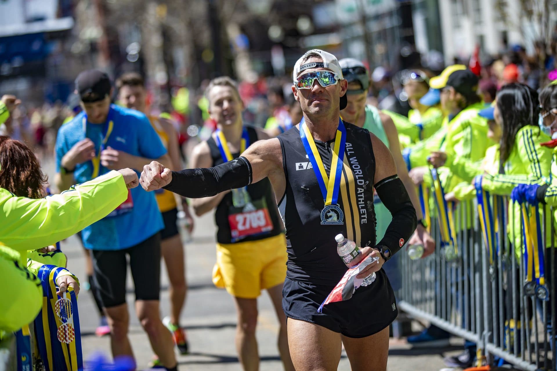 Kenneth Jones gets a fist bump from a Boston Marathon volunteer after he finished the race. (Jesse Costa/WBUR)