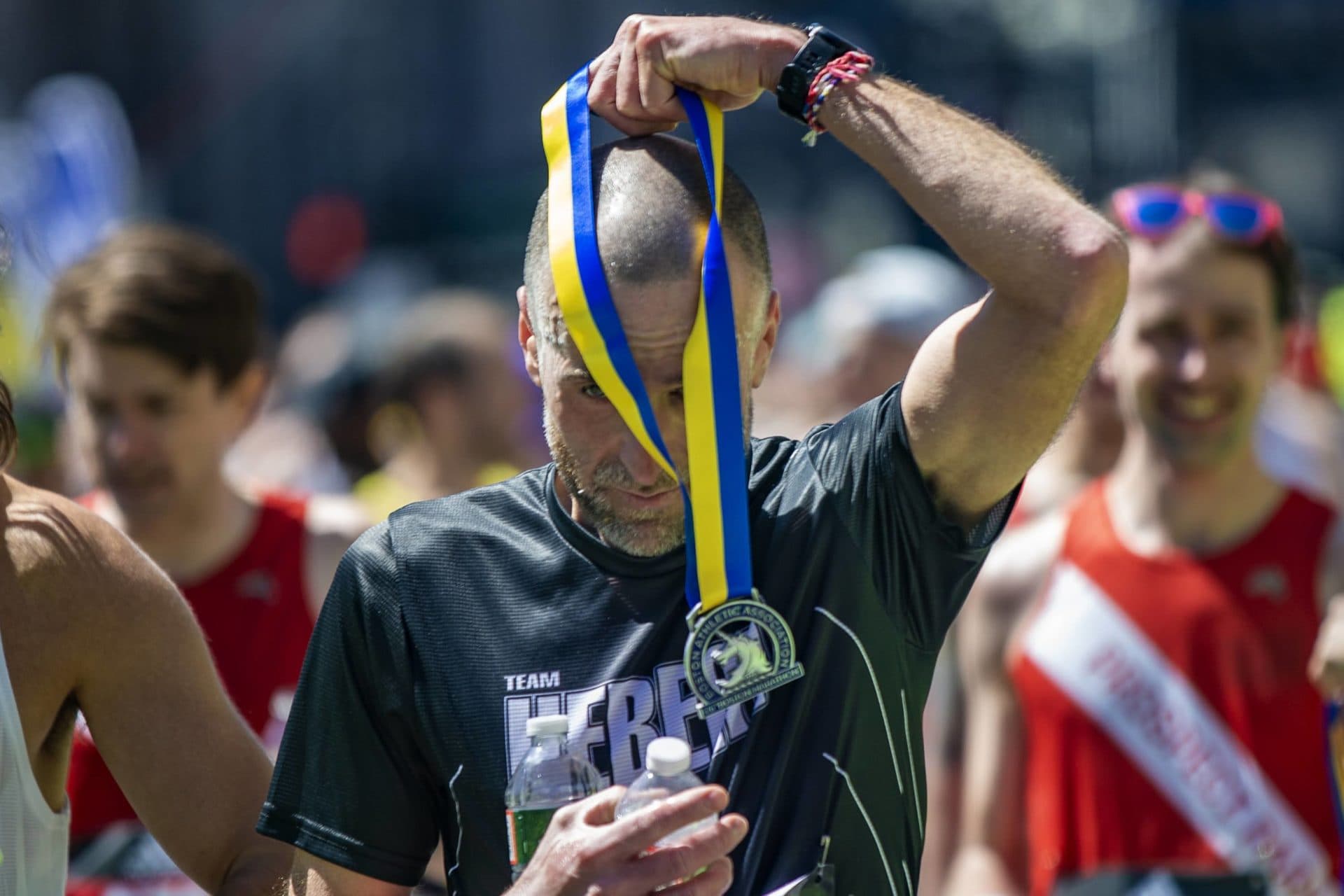 Sylvain Viillancourt places a Boston Marathon medal over his head after finishing the race. (Jesse Costa/WBUR)