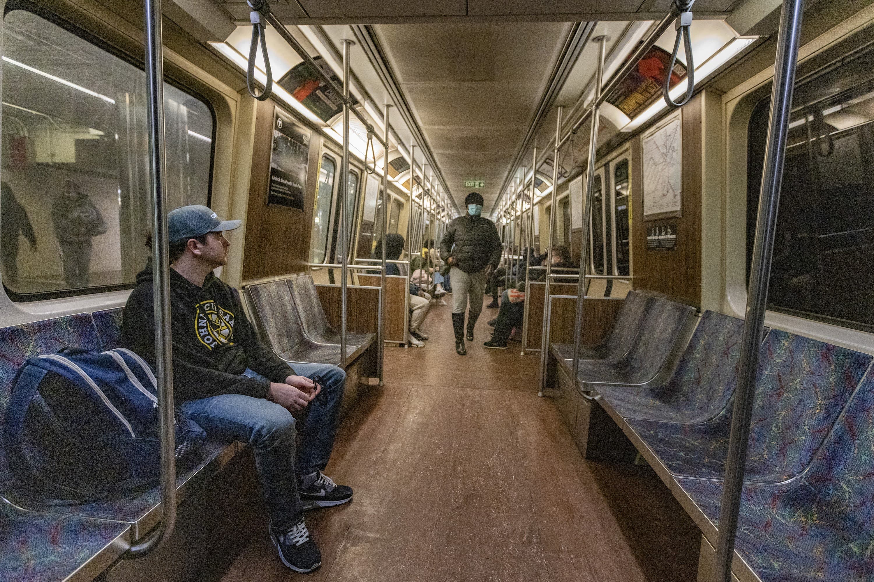 An unmasked rider watches as a masked person walks down the aisle to take a seat on an Orange Line train the first day the mask mandate has been lifted for traveling on the MBTA. (Jesse Costa/WBUR)
