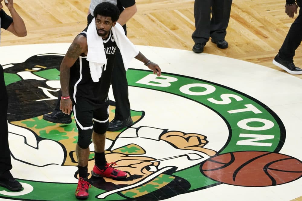Brooklyn Nets guard Kyrie Irving scrapes his foot on the Boston Celtics logo at mid-court after they defeated the Celtics in Game 4 during an NBA basketball first-round playoff series, Sunday, May 30, 2021, in Boston. (AP Photo/Elise Amendola)