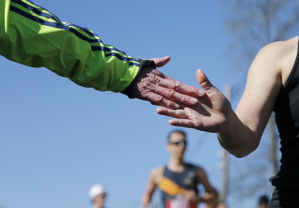 A volunteer offers a high-five to a runner during the 126th Boston Marathon. (Mary Schwalm/AP)