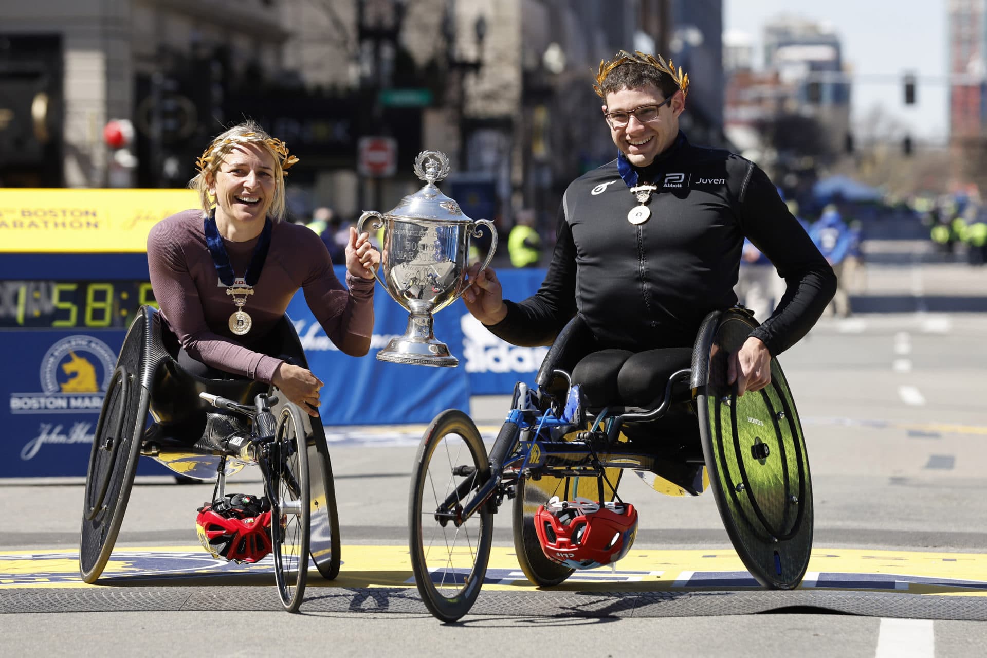 Manuela Schar, of Switzerland, left, and Daniel Romanchuck, of the United States, hold the trophy after winning the men's and women's wheelchair divisions of the 126th Boston Marathon. (Winslow Townson/AP)
