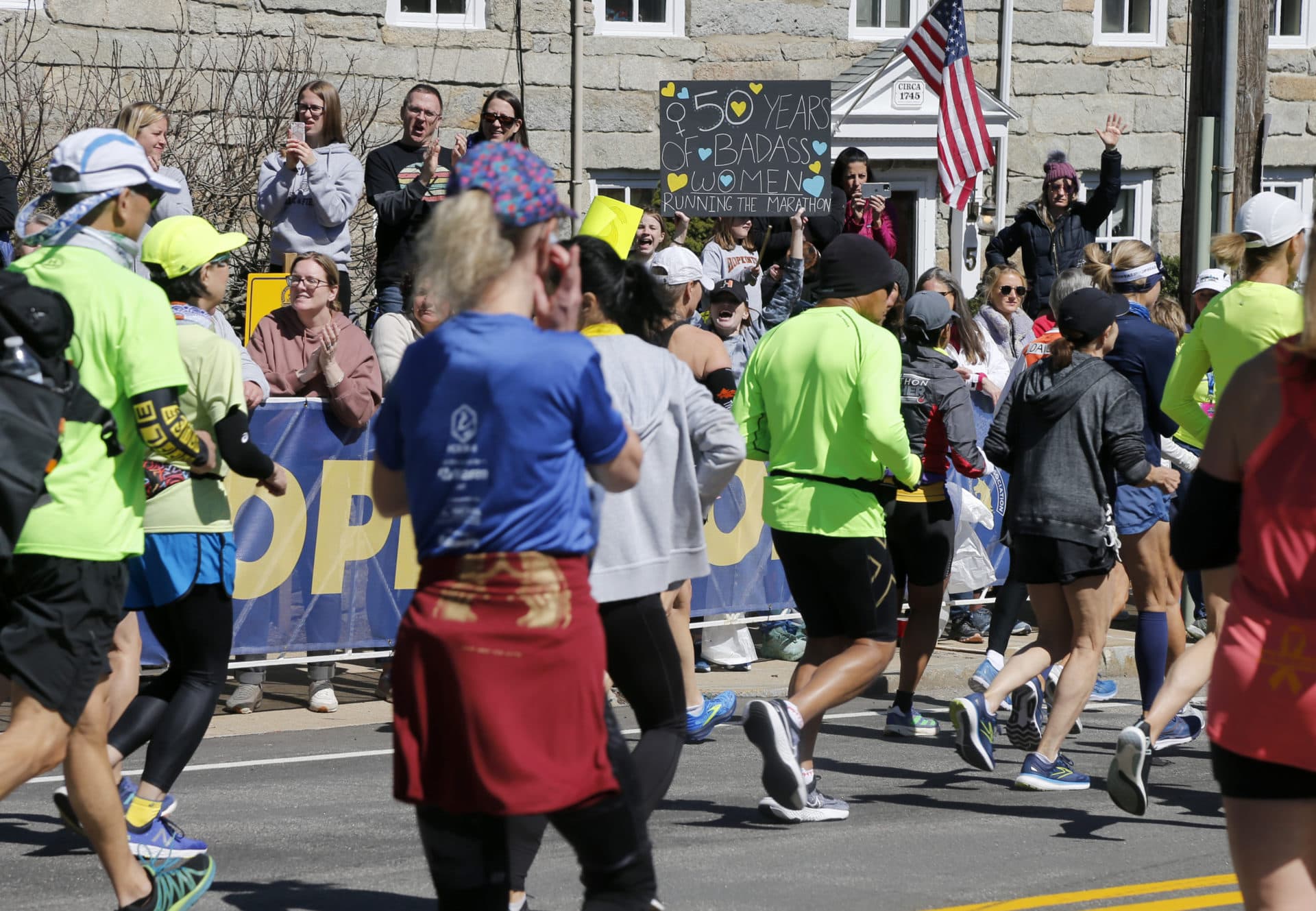 Runners in the 126th Boston Marathon pass a supporter holding a sign honoring the 50th anniversary of women's participation. (Mary Schwalm/AP)