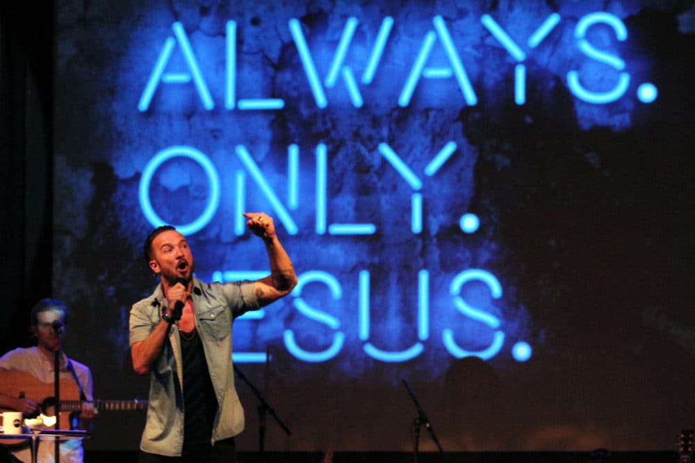 In this July 14, 2013 photo, Pastor Carl Lentz, foreground, leads a Hillsong NYC Church service at Irving Plaza in New York. With his half-shaved head, jeans and tattoos, Lentz doesn't look like the typical religious leader. But with its concert-like atmosphere and appeal to a younger demographic, his congregation, Hillsong NYC, is one of the fastest growing evangelical churches in the city. (Tina Fineberg/AP)