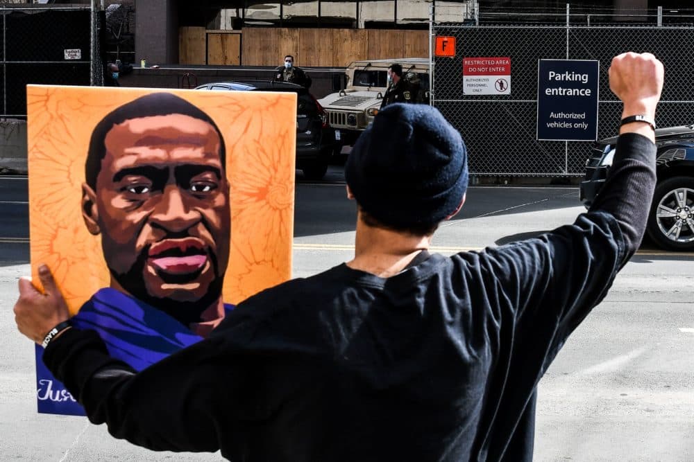A demonstrator holds a portrait of George Floyd in March 2021 in Minneapolis. An investigation sparked by Floyd's death found the city's police department had arrested and killed people of color at much higher rates than white people. (Chandan Khanna / AFP)