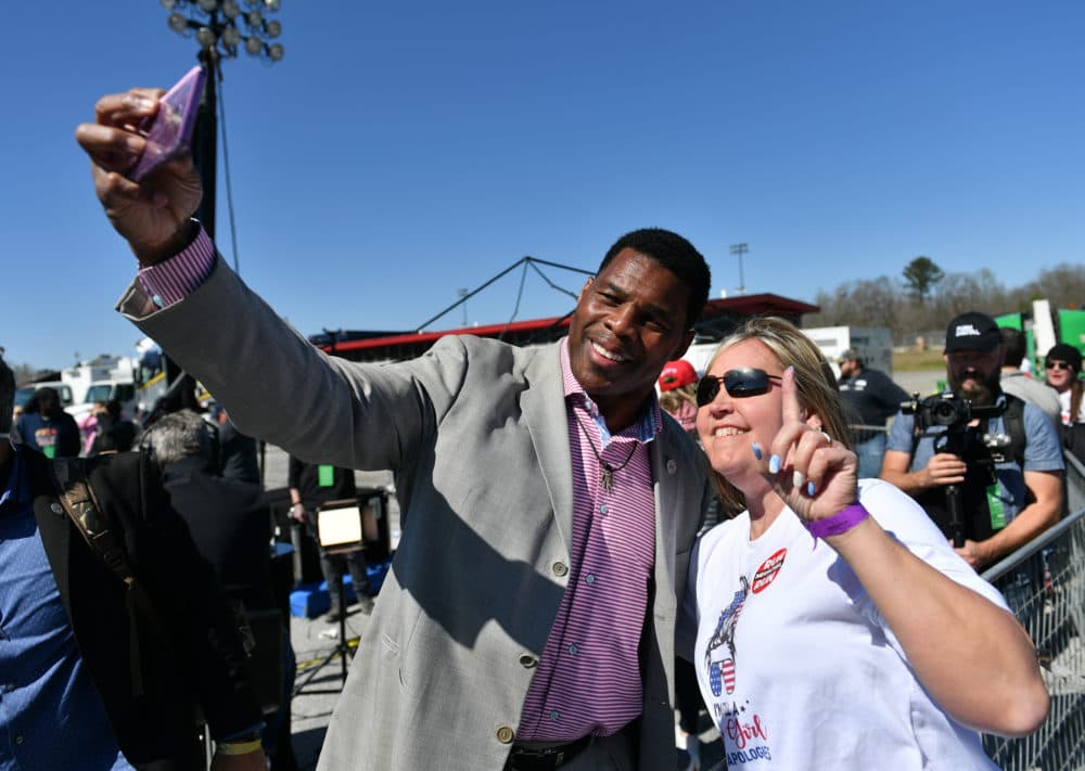 Republican Senate candidate Herschel Walker and a woman take a selfie during former US President Donald J Trump's &quot;Save America&quot; rally with David Perdue, Burt Jones, Marjorie Taylor Greene and Vernon Jones in Commerce, GA, on March, 26, 2022. (Peter Zay/Anadolu Agency via Getty Images)