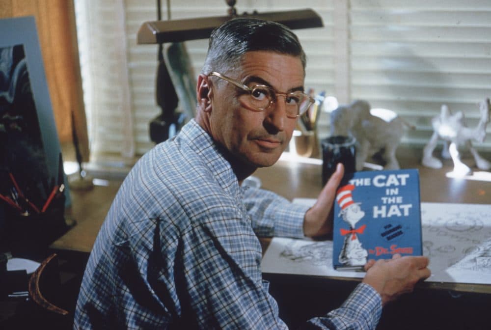 Theodor Seuss Geisel, (1904—1991) sits at his drafting table in his home office with a copy of his book, 'The Cat in the Hat', La Jolla, California, April 25, 1957. (Gene Lester/Getty Images)