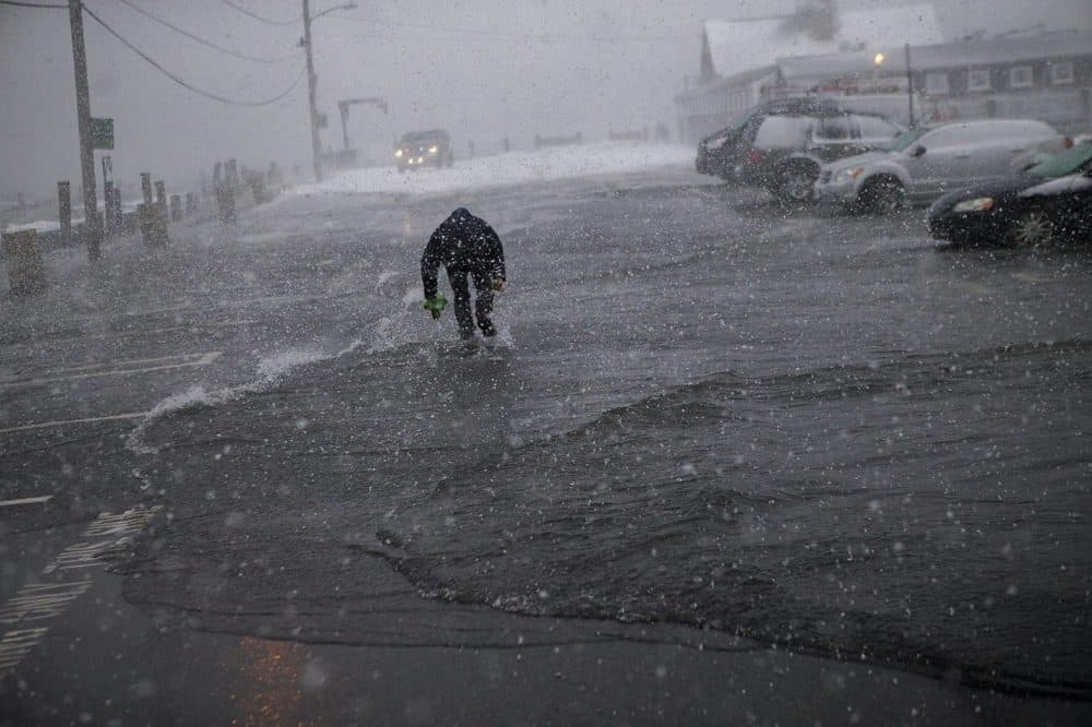 Joe Ferry, of Rockport, runs between waves to retrieve his car before it get submerged by ocean water in January 2018. (Jesse Costa/WBUR)