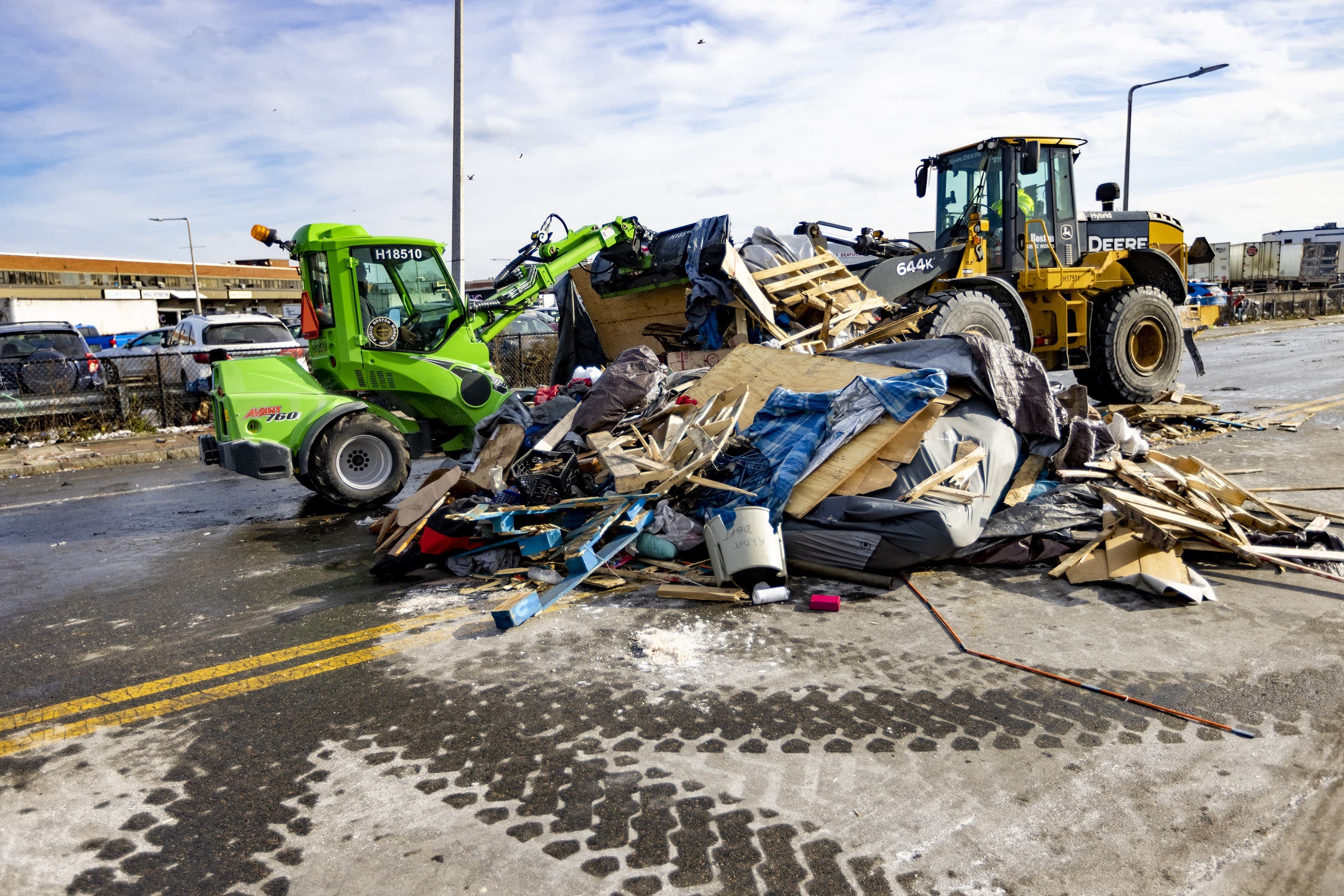 In this WBUR file photo, two construction trucks remove a pile of debris from the tent encampment near the so-called "Mass. and Cass' area in January 2022. (Jesse Costa/WBUR)