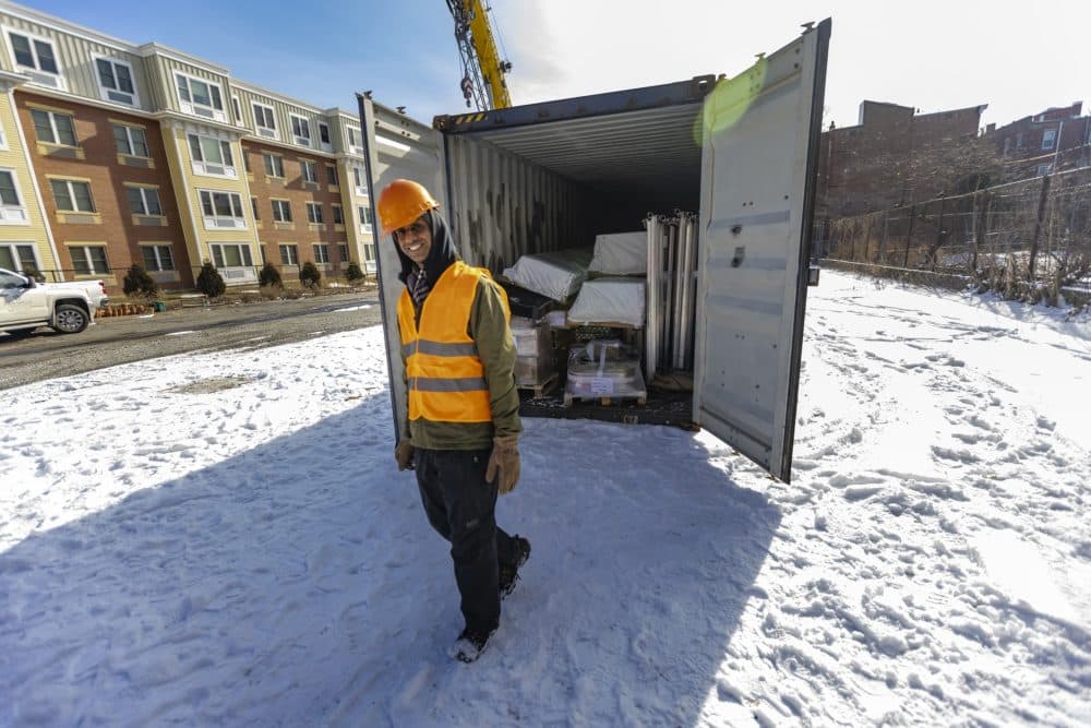 A smiling Kannan Thiruvengadam walks away from the shipping container after inspecting it’s contents. (Jesse Costa/WBUR)