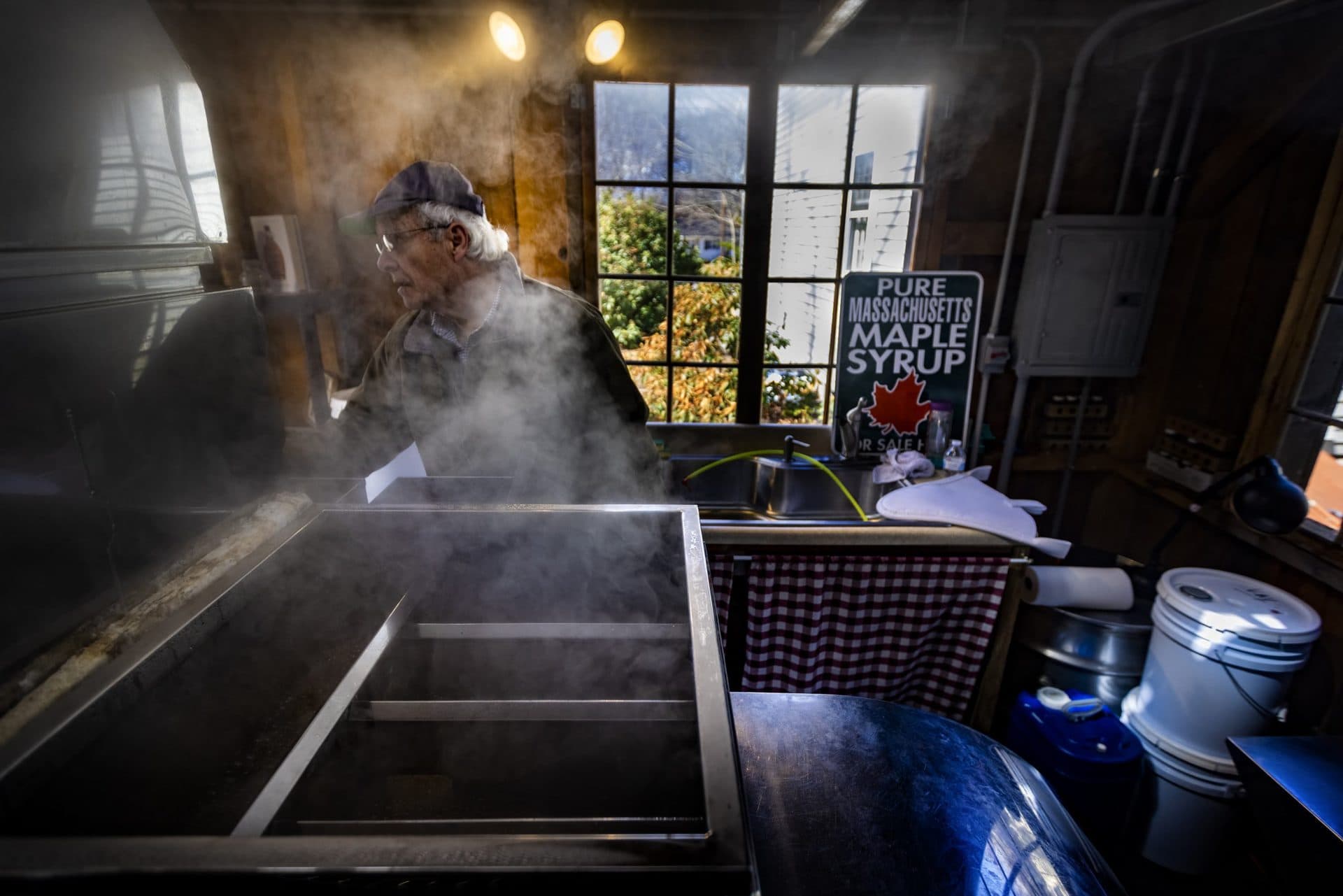 Ronald Kay checks the evaporator in the maple sugar shack at Maynard Maple to process sap he’s collected to make locally-sourced maple syrup. (Jesse Costa/WBUR)