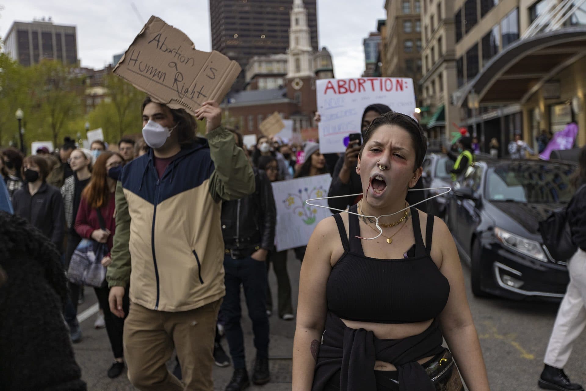 Samantha Mahoney wears a clothes hanger around her neck and marches with thousands of others down Tremont Street during the Defend Abortion Rights rally at the Massachusetts State House. (Jesse Costa/WBUR)