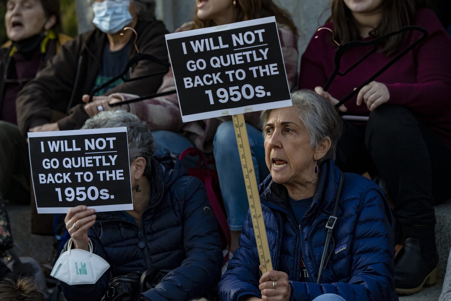 Two protesters hold signs reading, “I will not go quietly back to the 1950’s” during the Defend Abortion Rights rally at the Massachusetts State House. (Jesse Costa/WBUR)