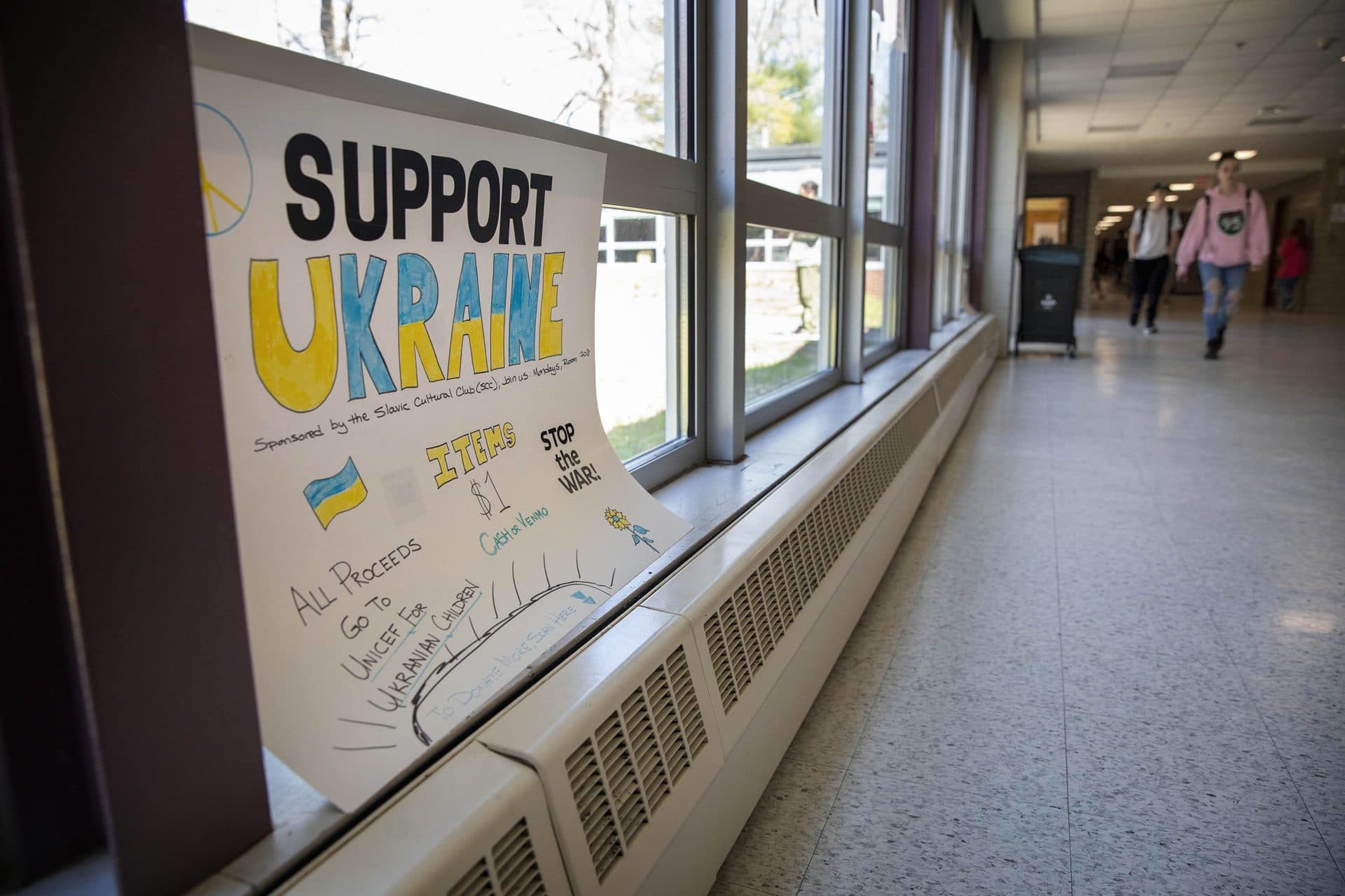 A poster in a hallway at Sharon High School asks students to donate funds in support of Ukrainian children. (Robin Lubbock/WBUR)