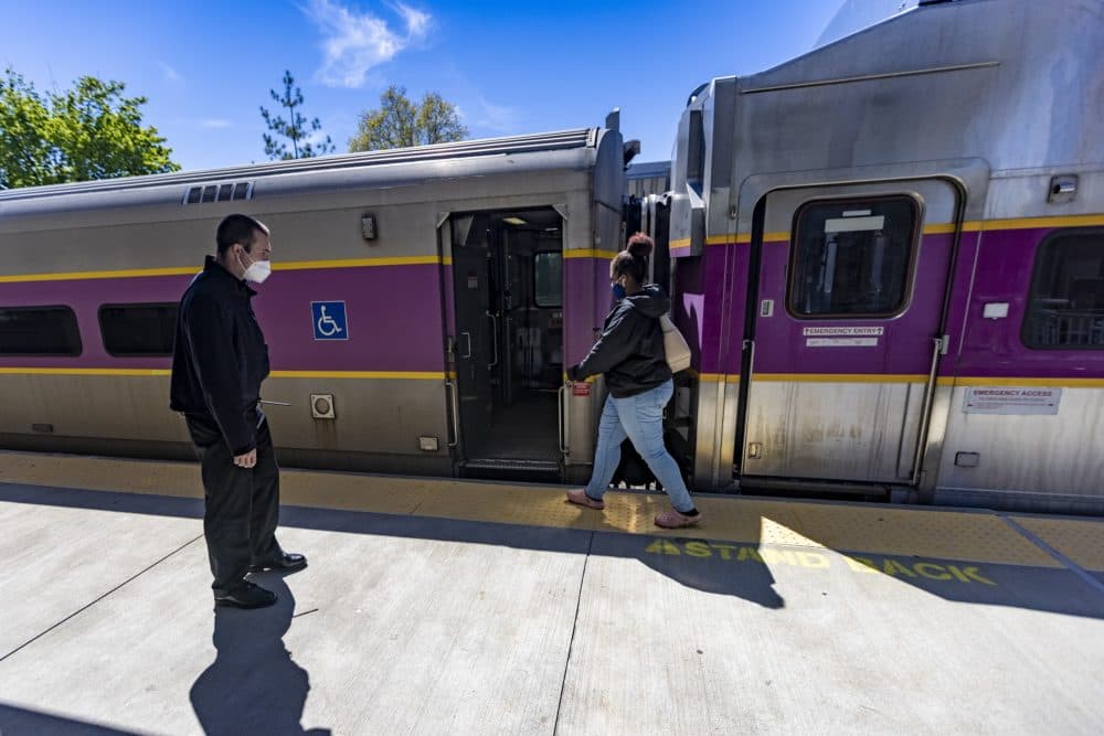 An MBTA commuter rail conductor watches as a passenger boards a train at the Talbot Avenue Commuter Rail Station. (Jesse Costa/WBUR)