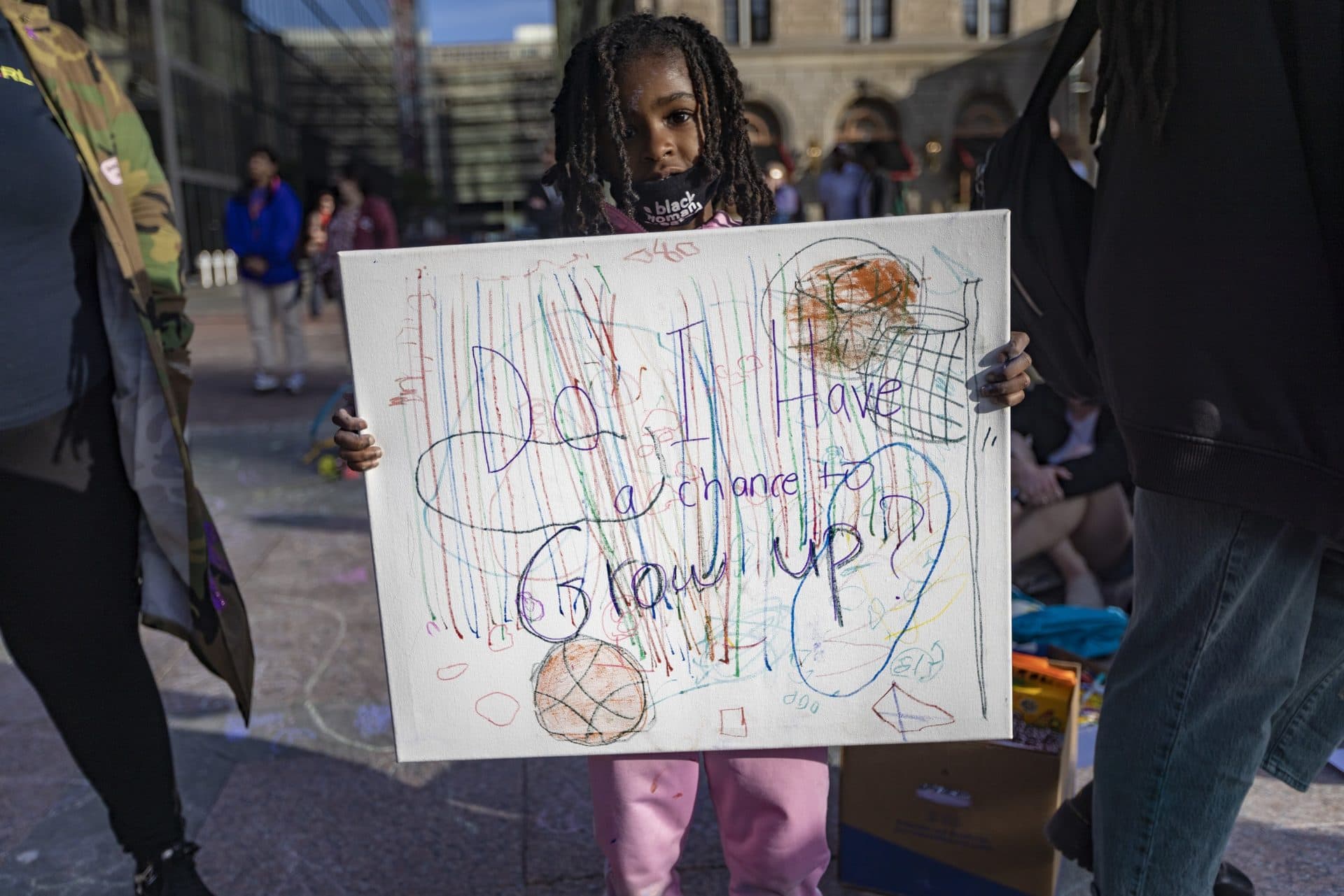 Chloe Matthews, 6, holds a sign that reads, “Do I have a chance to grow up?” (Jesse Costa/WBUR)