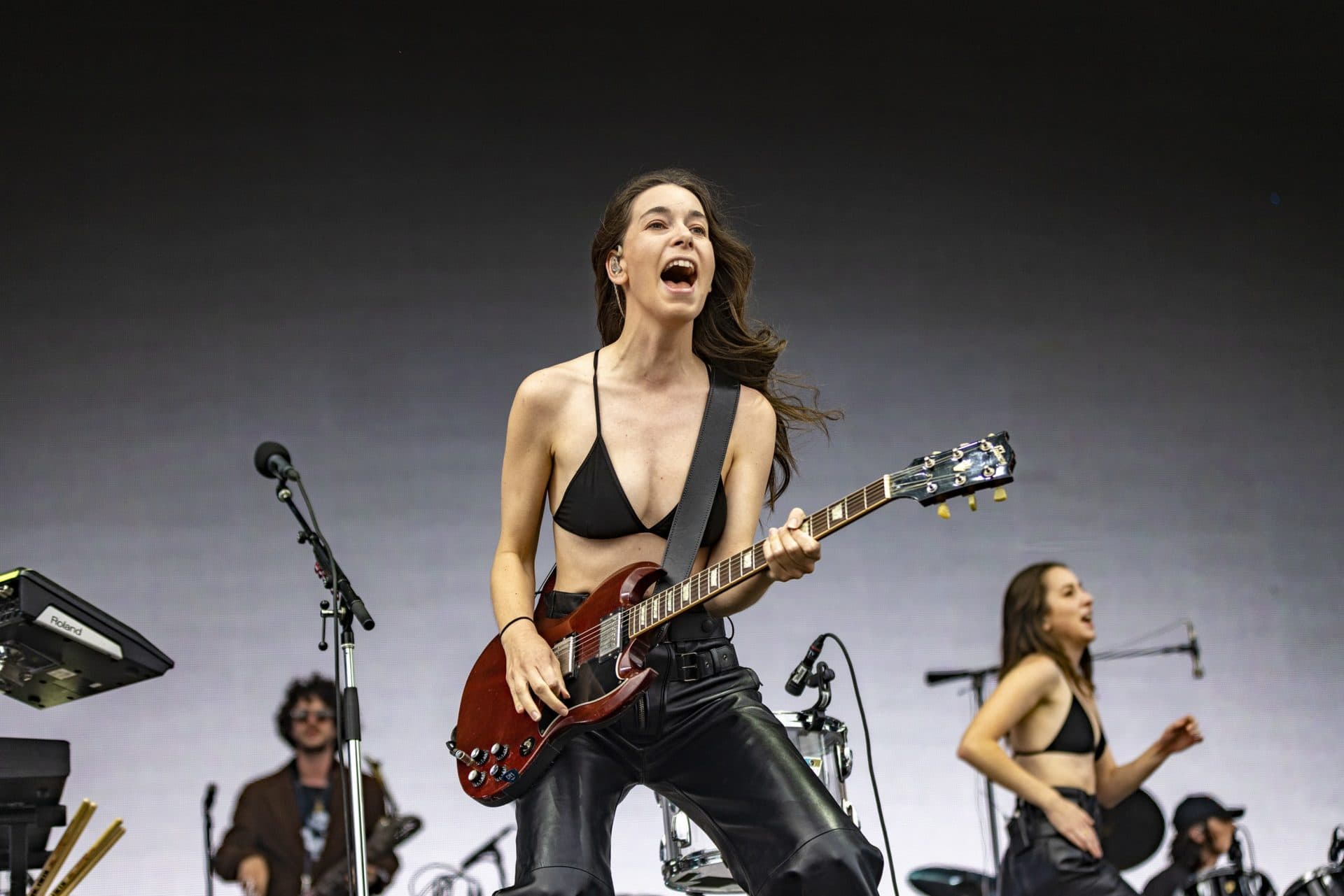 Danielle Haim plays guitar as sister Este runs out onto the stage at the beginning of their set at the Boston Calling Music Festival. (Jesse Costa/WBUR)