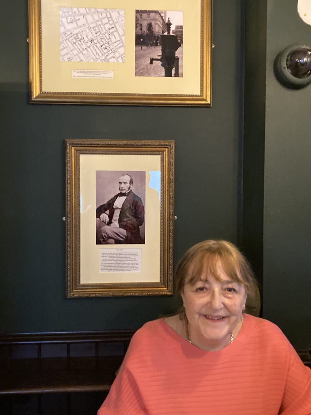 Retired epidemiologist Rosalind Stanwell-Smith of the John Snow Society, with a photo of Snow in the background. (Scott Tong/Here &amp; Now)