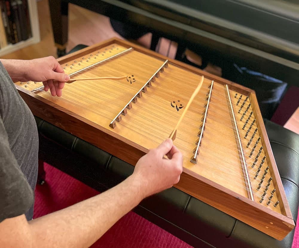 Composer Eric Shimelonis playing the hammered dulcimer: which consists of strings stretched over a trapezoid-shaped resonant sound board. (courtesy of Rebecca Sheir)