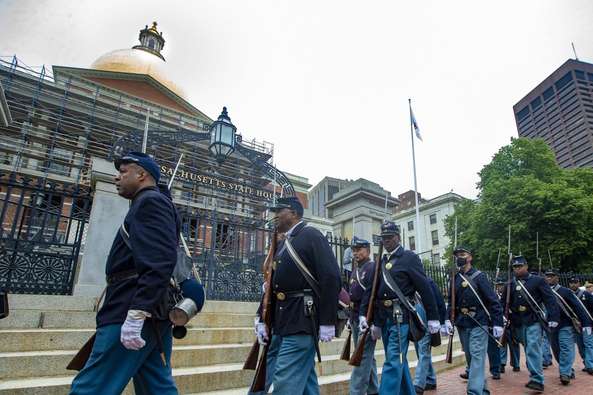 The procession of the 54th Massachusetts Volunteer Regiment marches past the front gates of the State House. (Jesse Costa/WBUR)