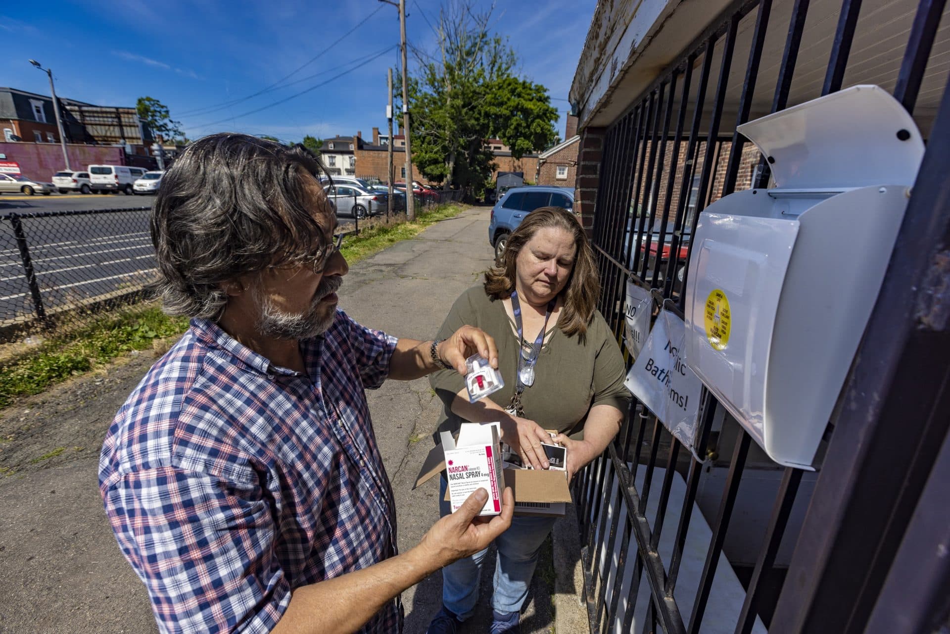 Pastor Roberto Silveira and Judy Gustafson, both with the Universal Missionary Church, regularly fill a church mailbox with naloxone for anyone to take. (Jesse Costa/WBUR)