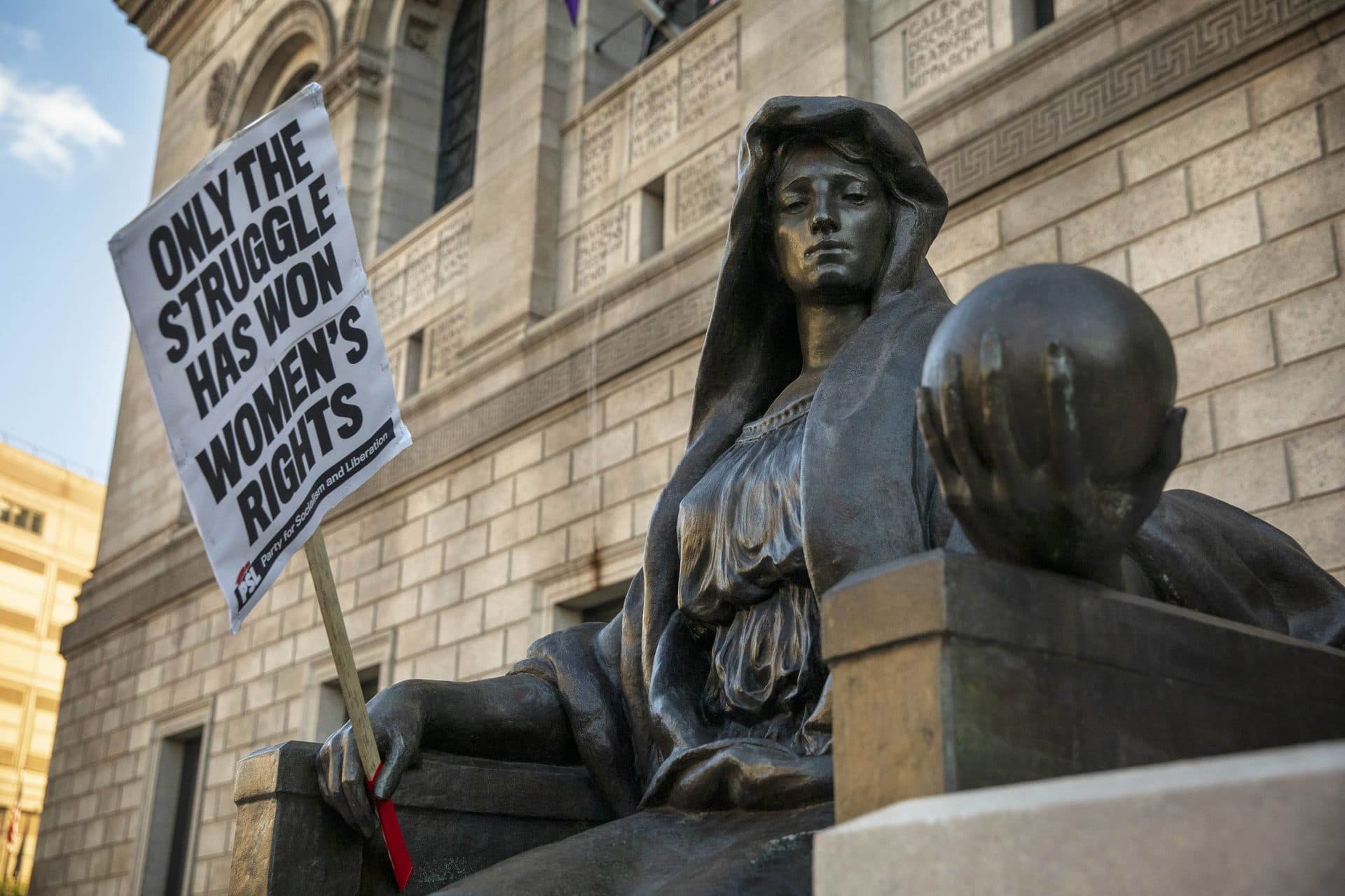 Abortion-rights protesters left one of their signs with one of the statues in front of Boston Public Library. (Robin Lubbock/WBUR)