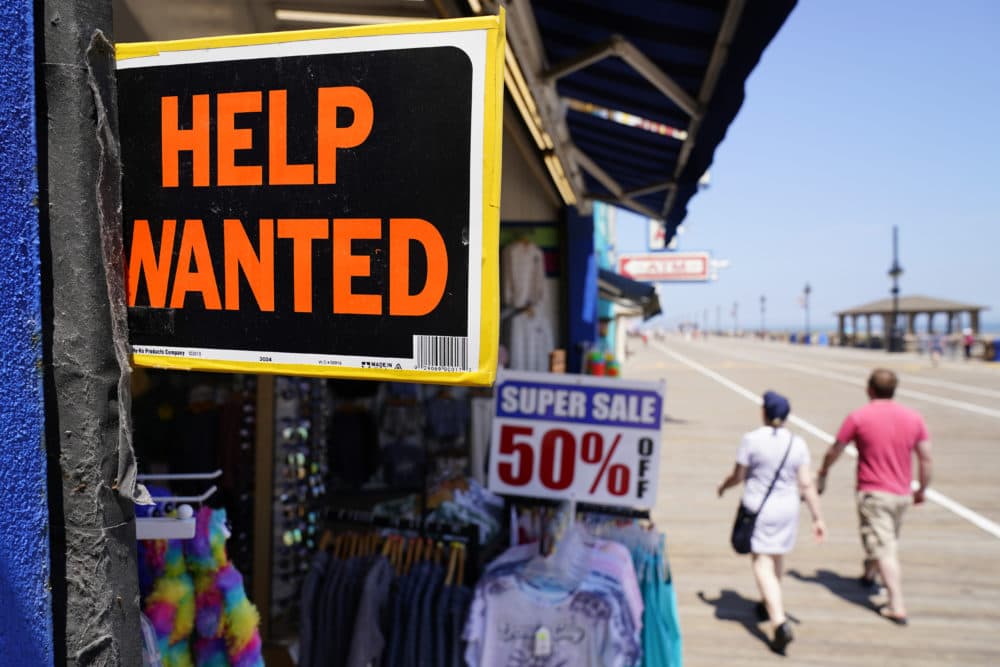 People walk past a help wanted sign in front of a souvenir shop along the boardwalk, Thursday, June 2, 2022, in Ocean City, N.J. Many seasonal businesses are struggling to find enough workers again this summer. (Matt Slocum/AP)
