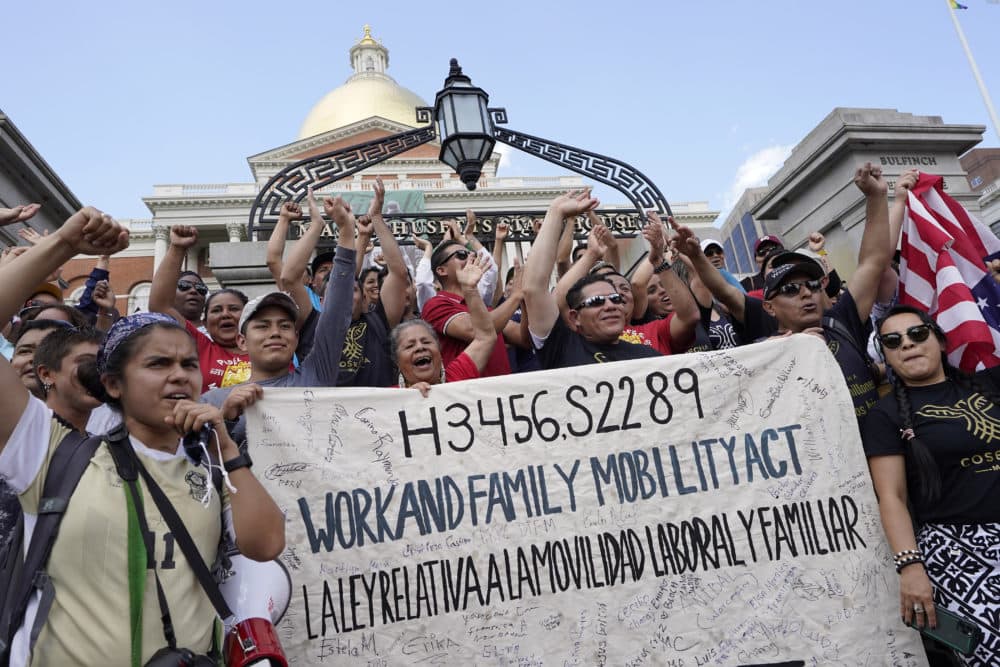 Demonstrators display a banner and chant slogans during a rally in front of the State House, in Boston on June 9, 2022, held in support of allowing immigrants in the country illegally to obtain driver's licenses in Massachusetts. (Steven Senne/AP)