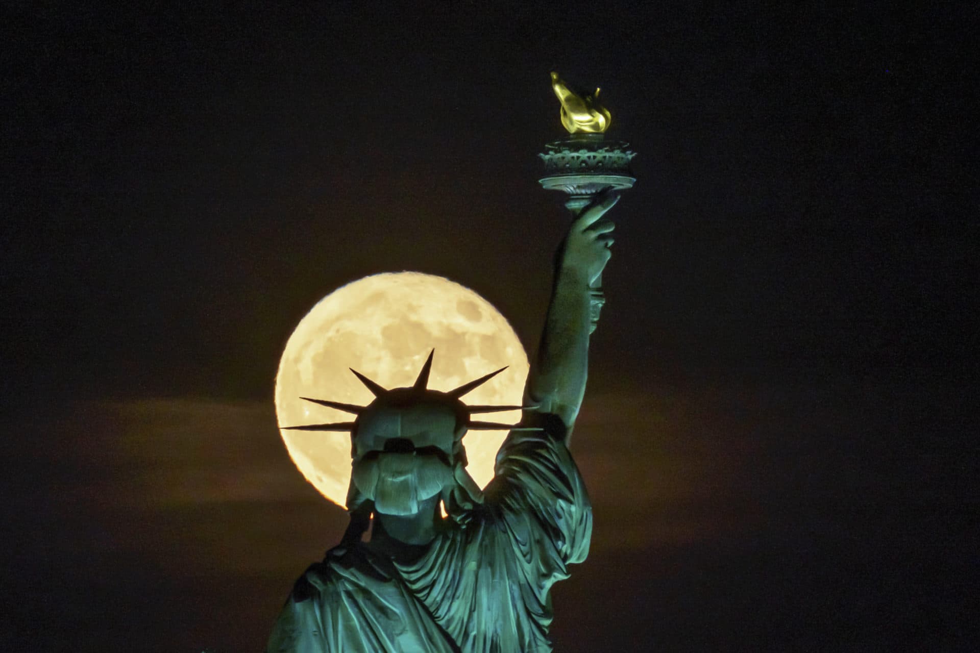 The strawberry supermoon rises in front of the Statue of Liberty in New York. (J. David Ake/AP)