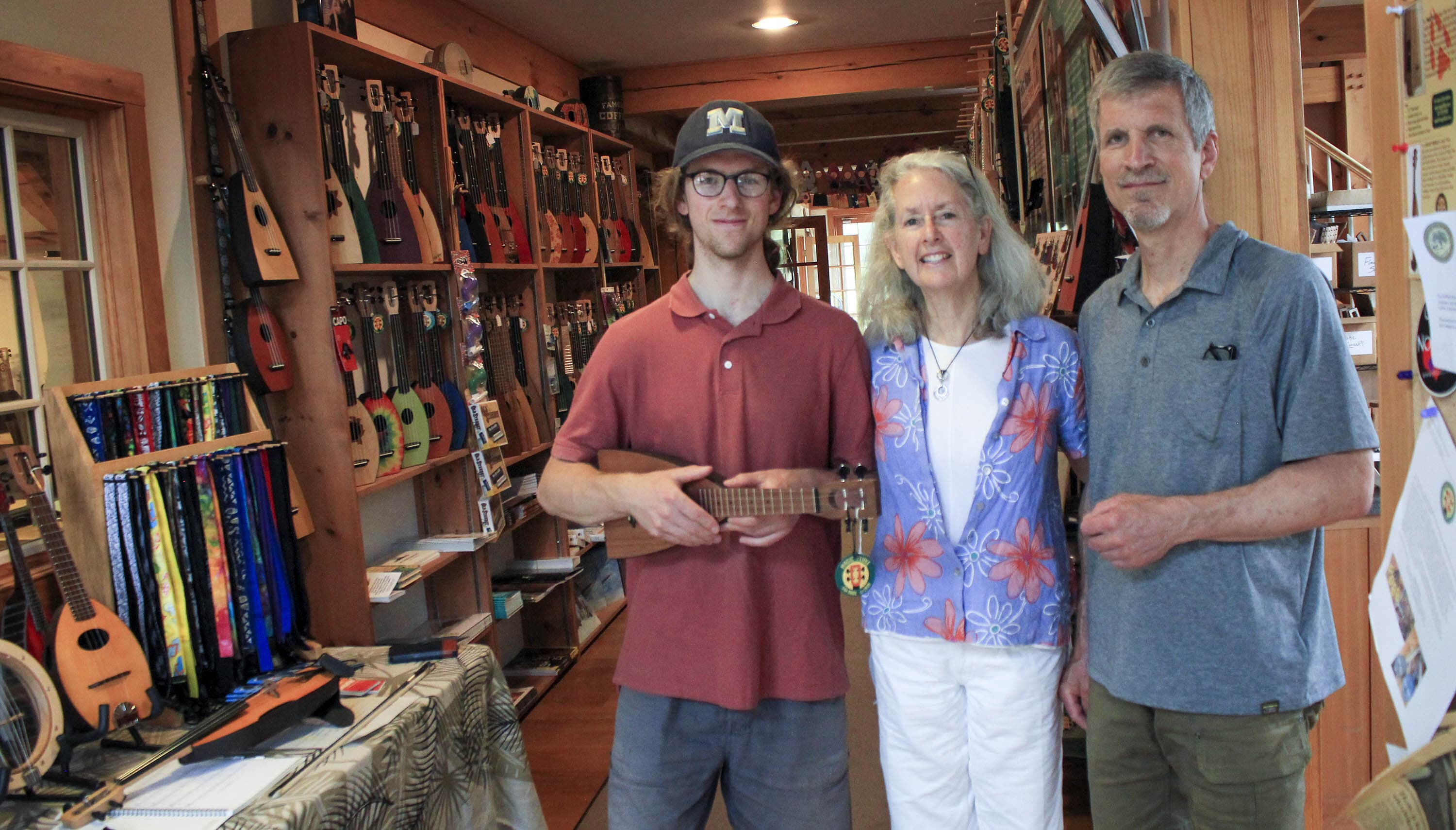 Josh, Phyllis, and Dale Webb stand in their store, The Magic Fluke, which sells handmade string instruments (Yasmin Amer / WBUR)