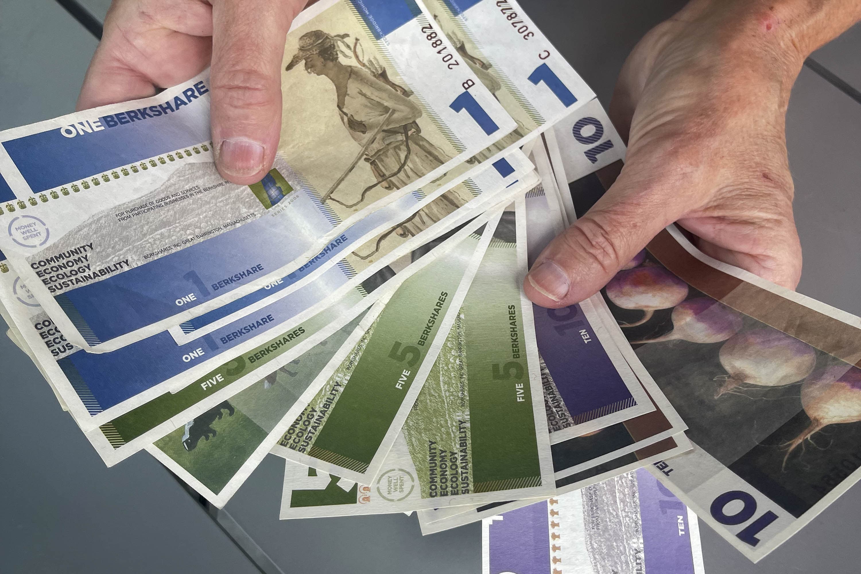 Leah Barber, a volunteer member of the BerkShares board, shows off the local currency in its paper form (Yasmin Amer / WBUR)